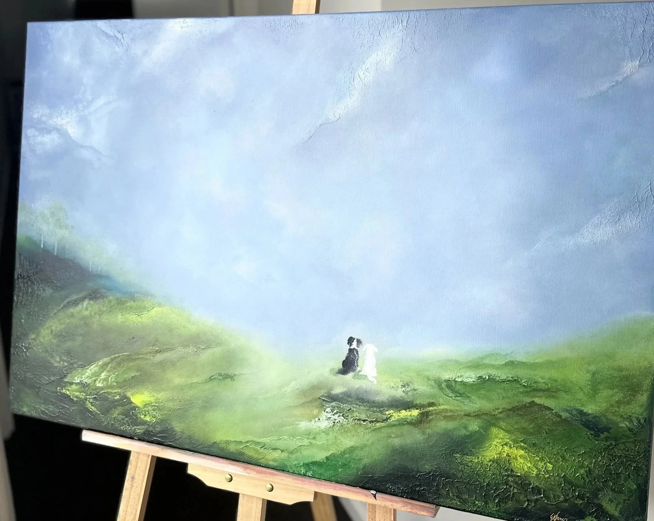 Painting of a scenic landscape with green rolling hills, a cloudy blue sky, and two dogs sitting on the grass.