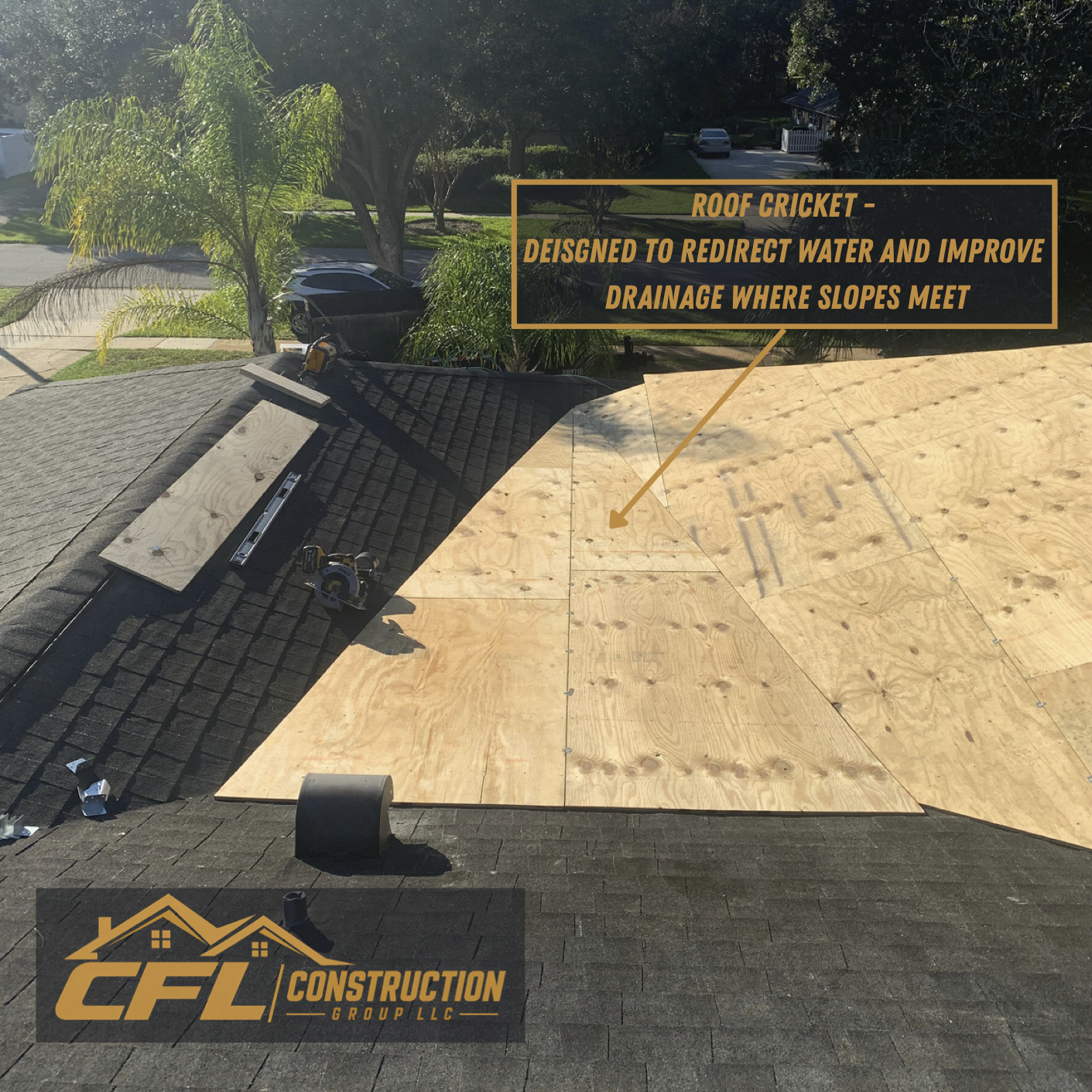 Roof under construction with plywood panels partially installed, showing a black shingled section, construction tools on the roof, and a note about roof cricket for water drainage exit. Trees and a neighborhood street are visible in the background.