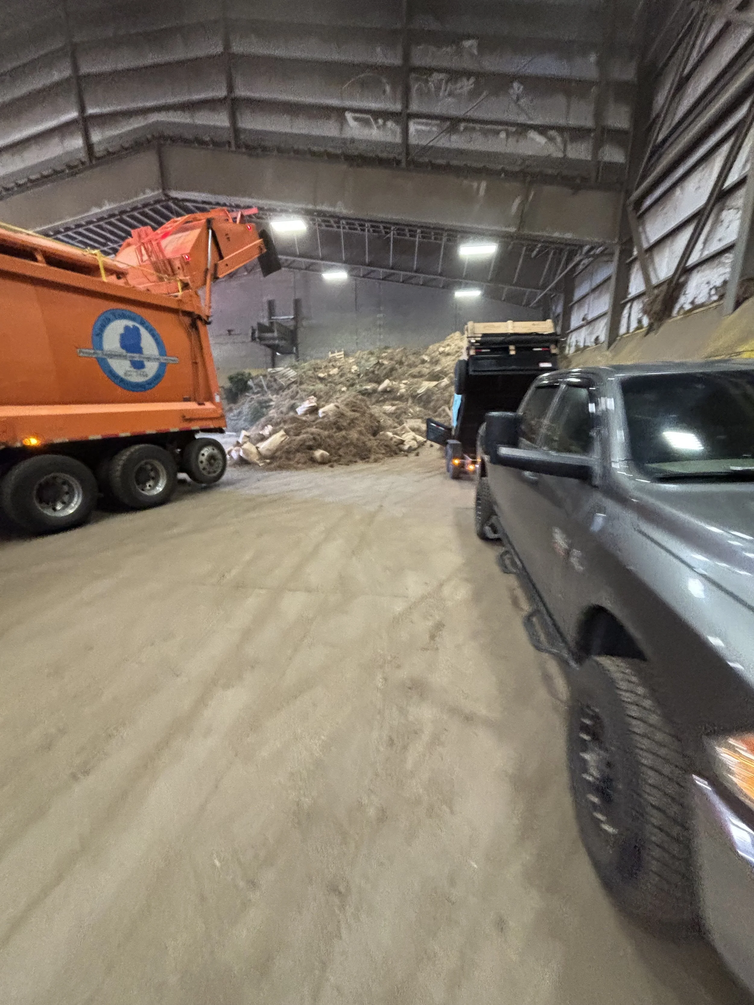Interior of a tunnel under construction or renovation with dirt piles, construction vehicles, and equipment.