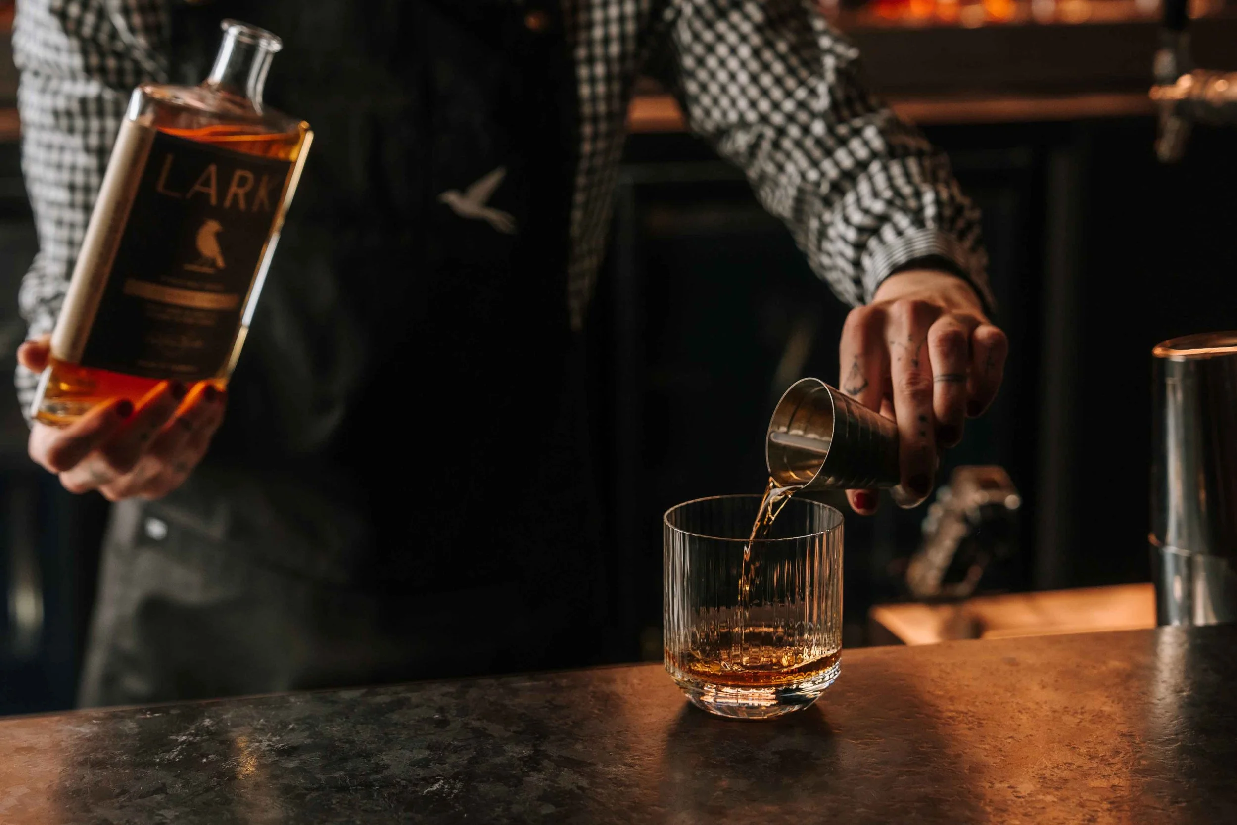 A bartender at Blackbird Melbourne pouring a spirit into a glass over ice