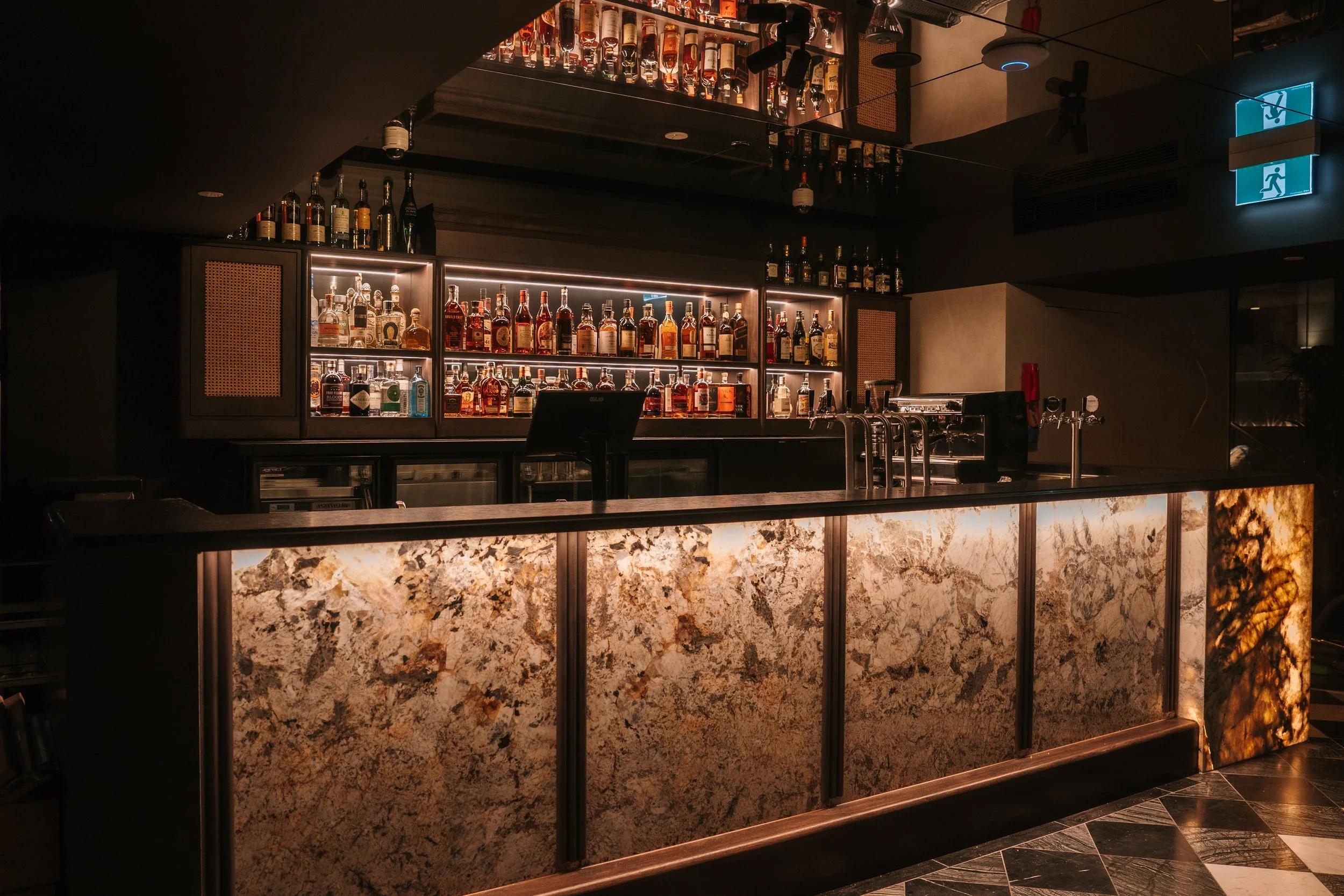 The lit stone-fronted bar at Blackbird Melbourne, shelves of spirits behind it