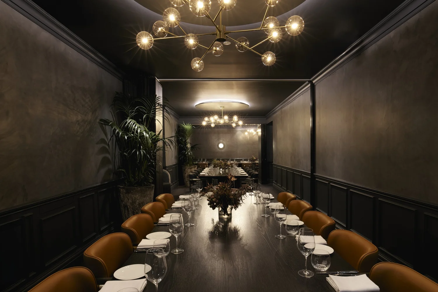 The full private dining floor seen down the length of the table, chandeliers receding
