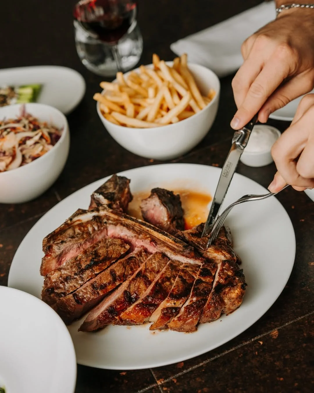 A steak being carved at a seated Christmas dinner at Blackbird Melbourne