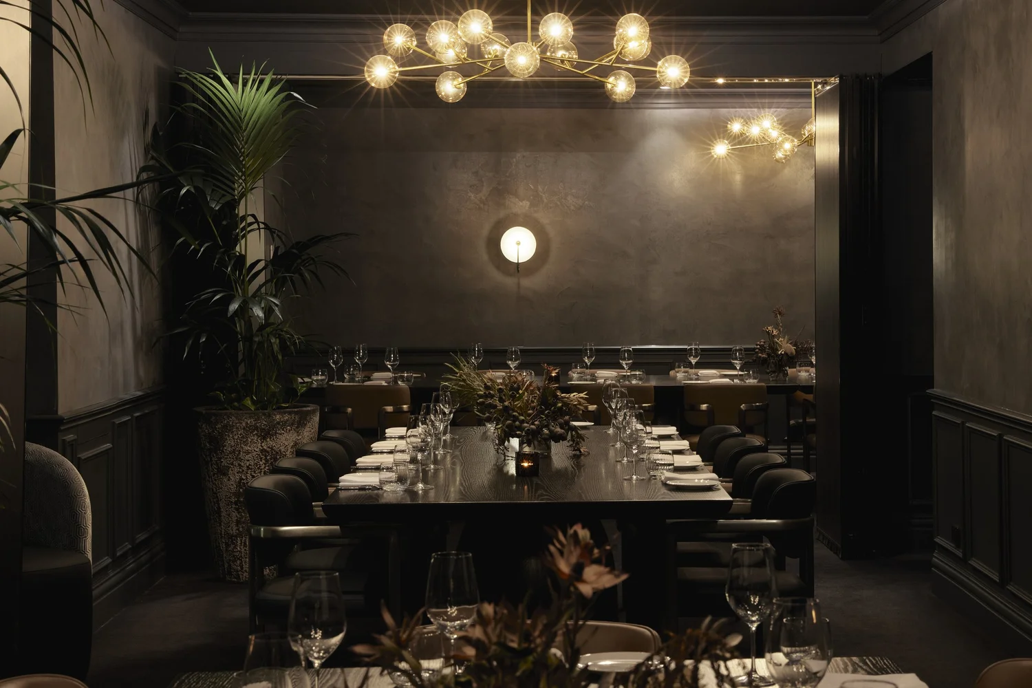 The private dining floor laid out as one continuous table beneath brass chandeliers