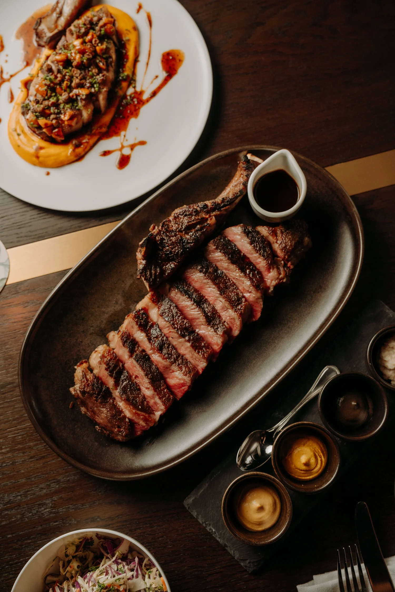 Wood-grilled steak served on a board with sauces