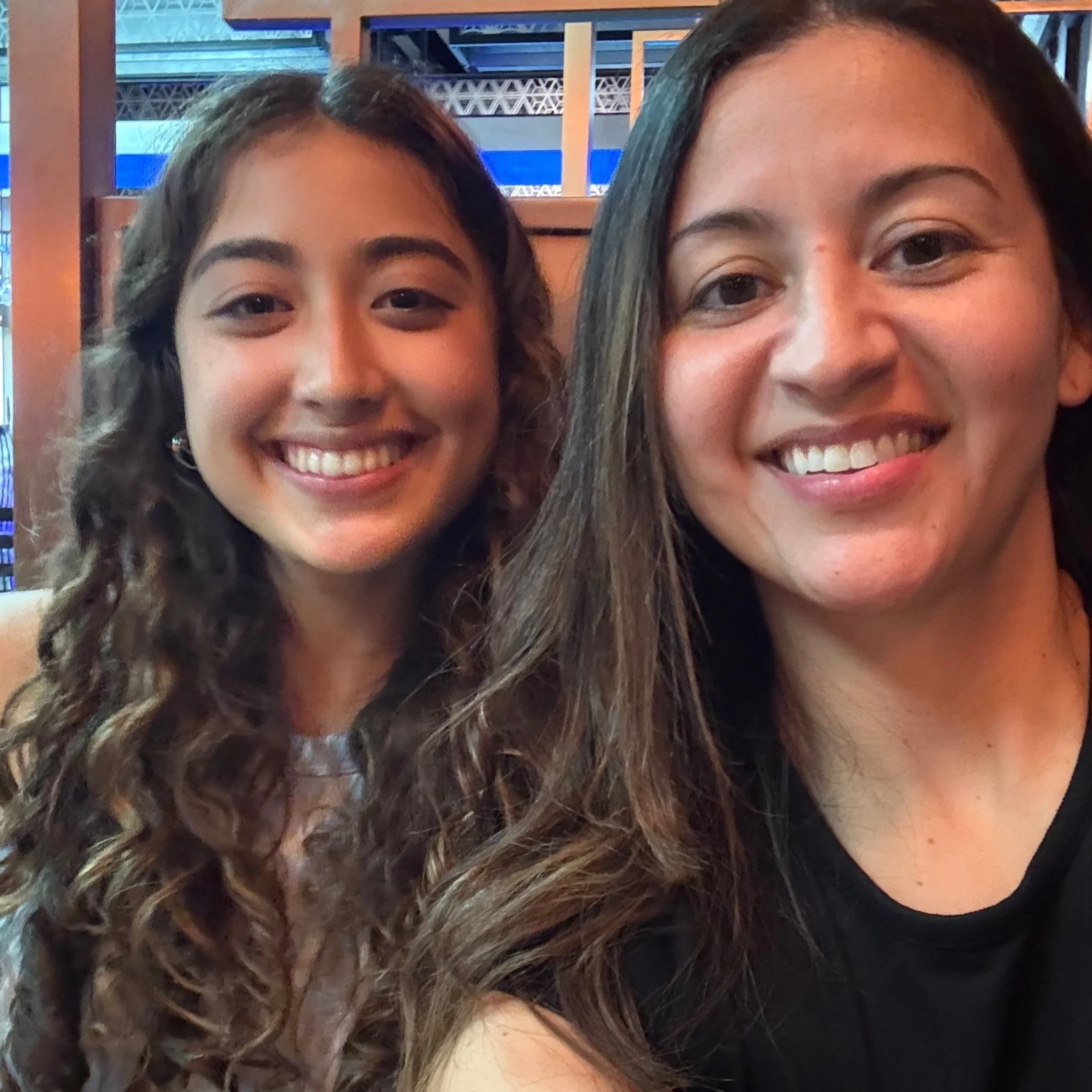 Two women smiling for a selfie in a restaurant setting.
