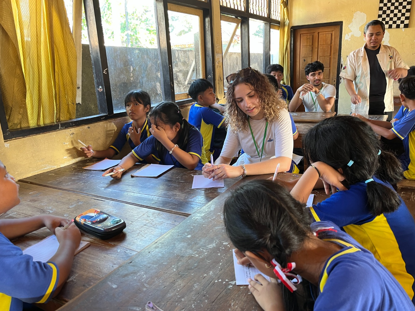 A boy working with wooden letter tiles while a teacher guides him during a literacy session