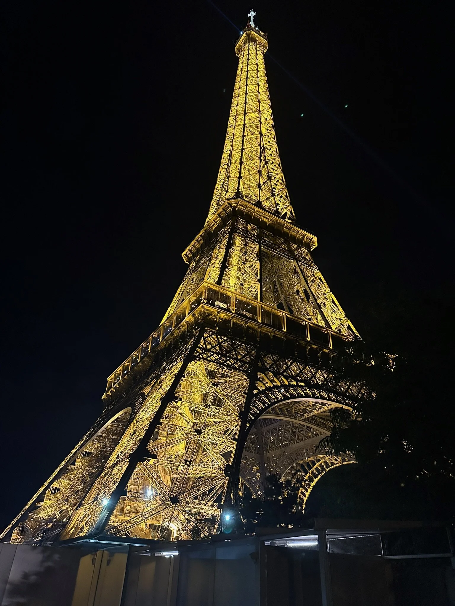 The Eiffel Tower illuminated at night with golden lights against a dark sky.