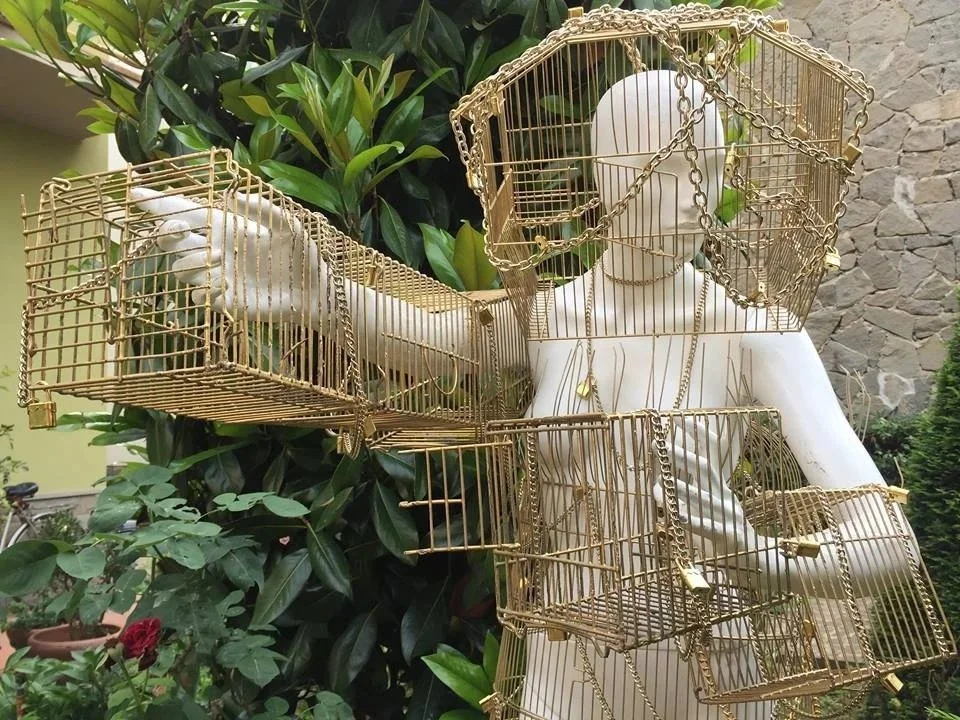 DANNATA UTOPIA - Installazione 2018
"Dannata Utopia" nasce come riflessione sull'illusione del benessere costruito sul possesso e sull'apparenza.

Un manichino femminile a grandezza naturale è avvolto da gabbie e catene dorate: simboli di una ricchez