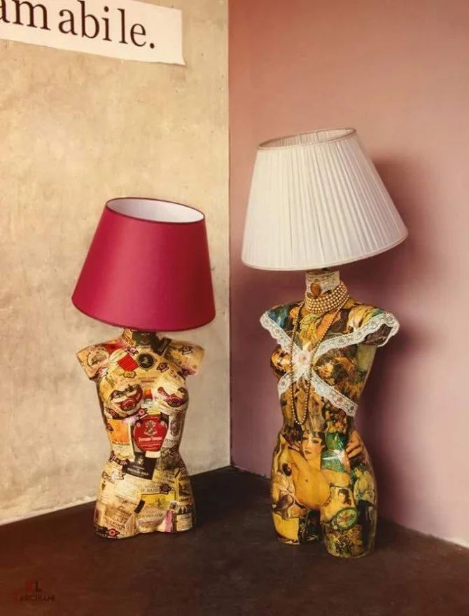 Due lampade da tavolo con basi a forma di busto femminile con stampa di pubblicità vintage e collage, una con paralume rosso e l'altra con paralume bianco.