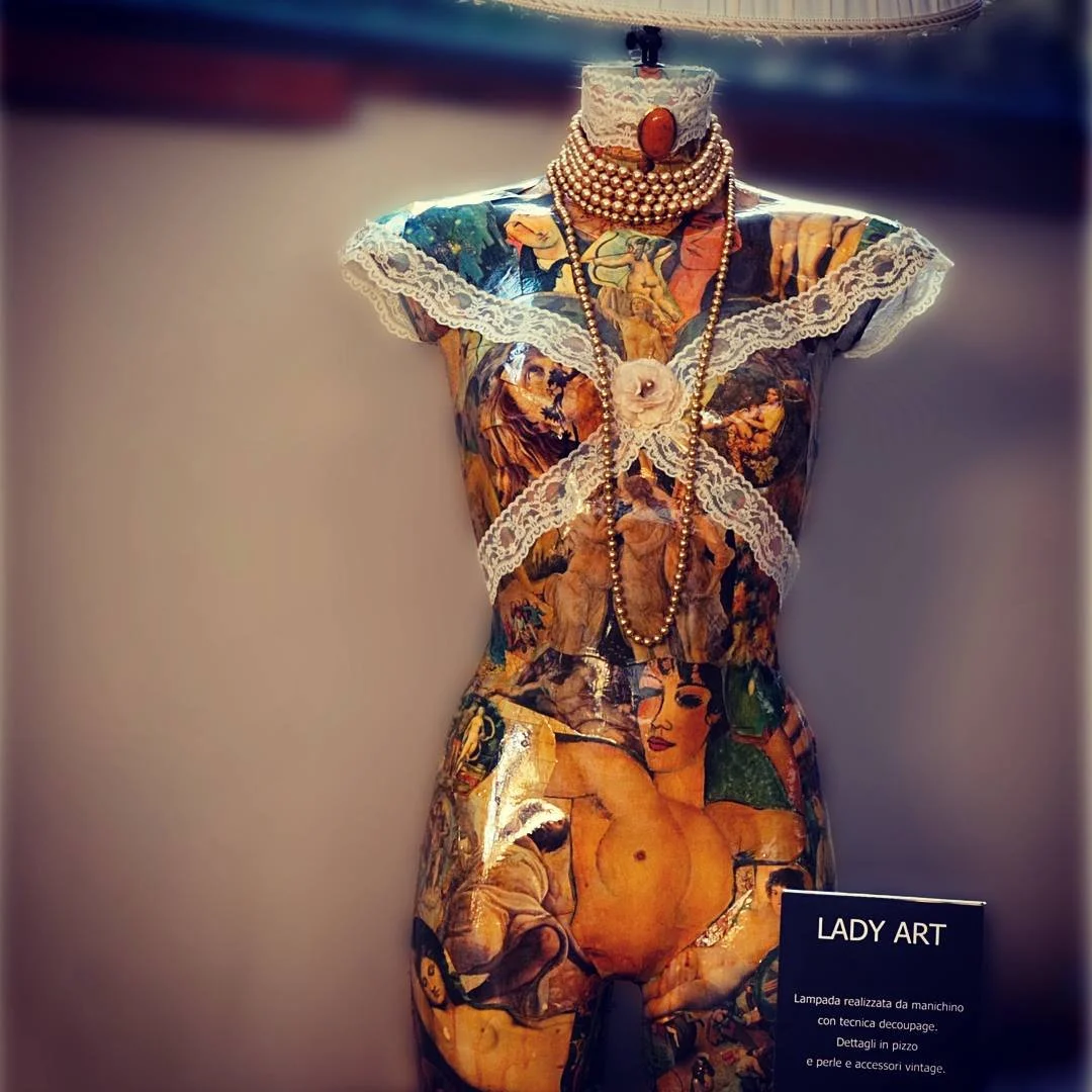Manichino vestito con decorazioni artistiche, con collane di perle e dettagli vintage, in esposizione in un museo o galleria d'arte.
