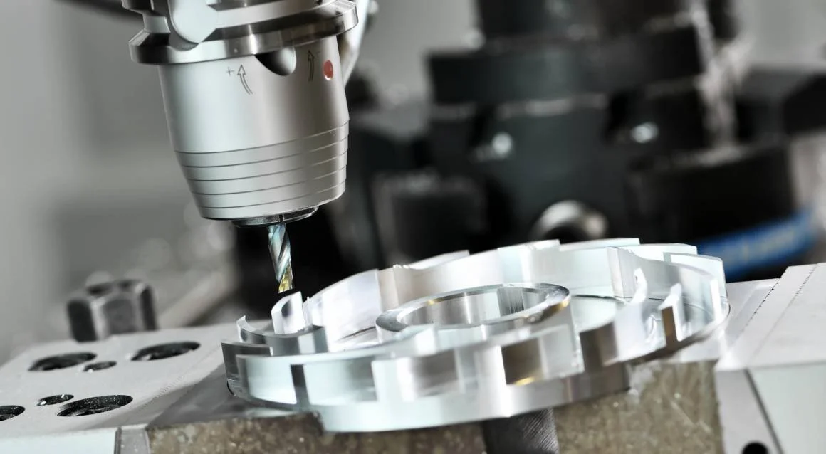 A close-up of a CNC machine cutting a circular metal part with a drill bit.