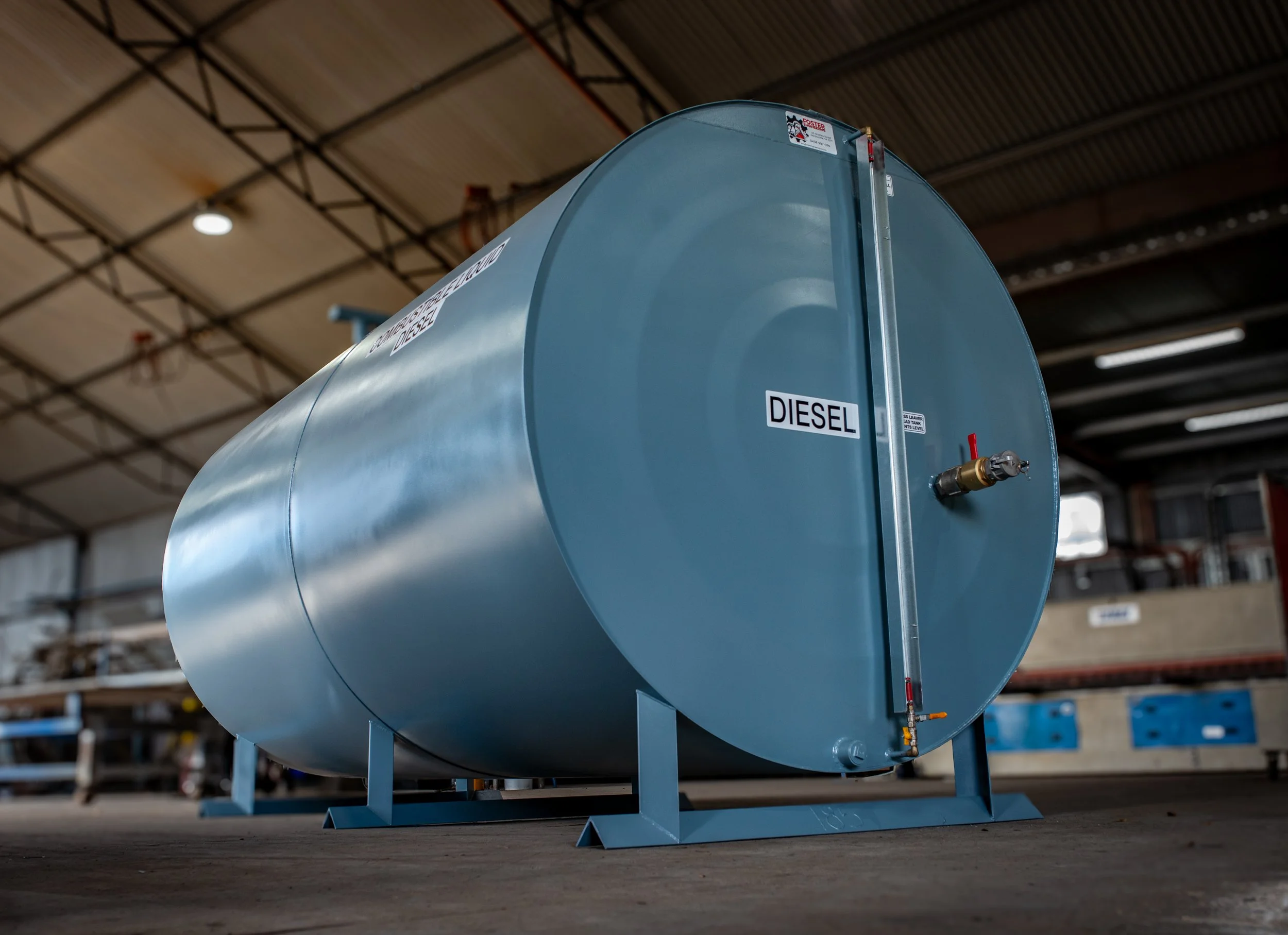 Large blue fuel tank labeled for diesel, inside an industrial warehouse.
