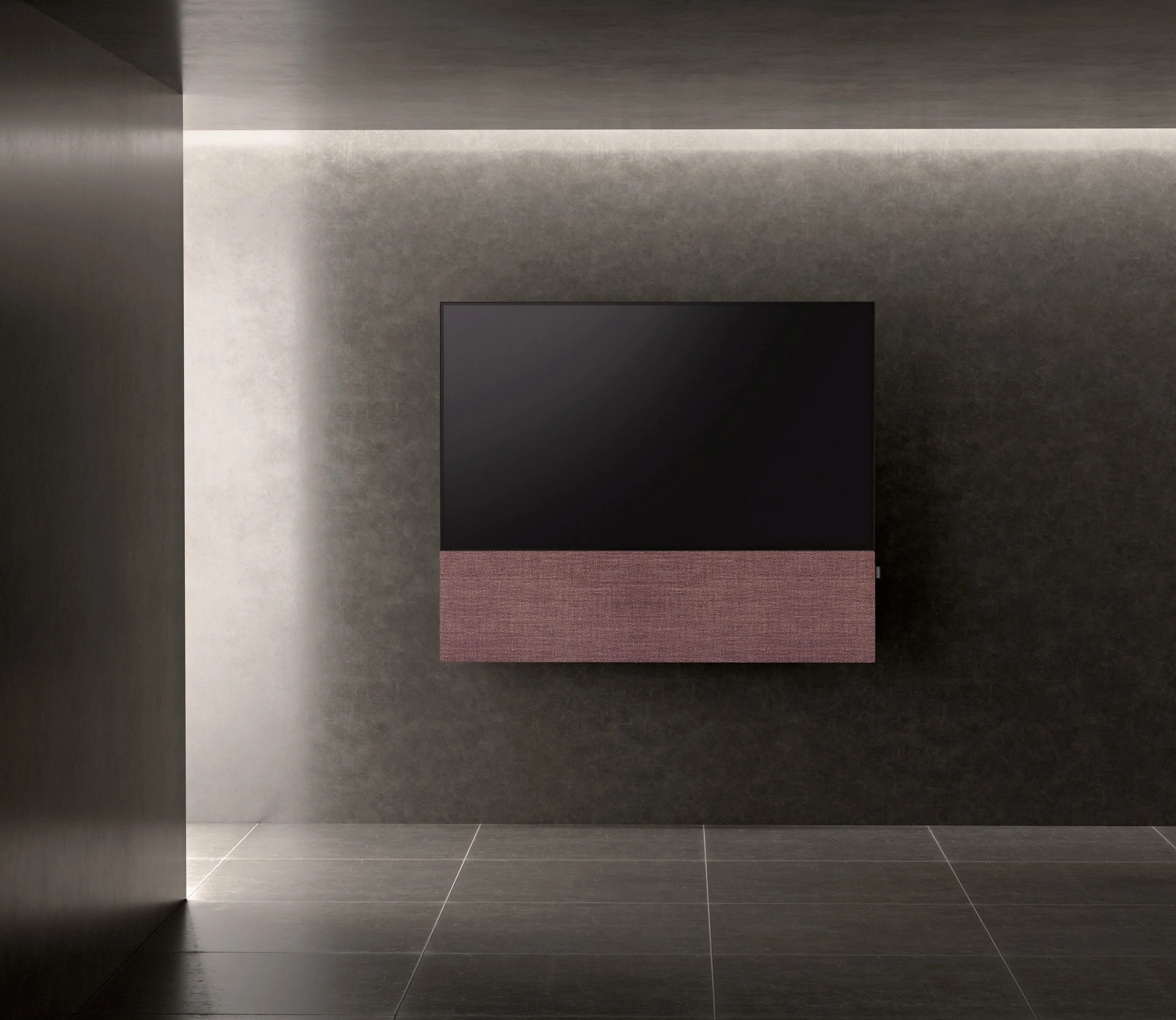 Ein moderner, wandmontierter Fernseher mit einem abnehmbaren Lautsprecher darunter in einem minimalistischen Raum mit dunklen Wänden und Bodenfliesen.