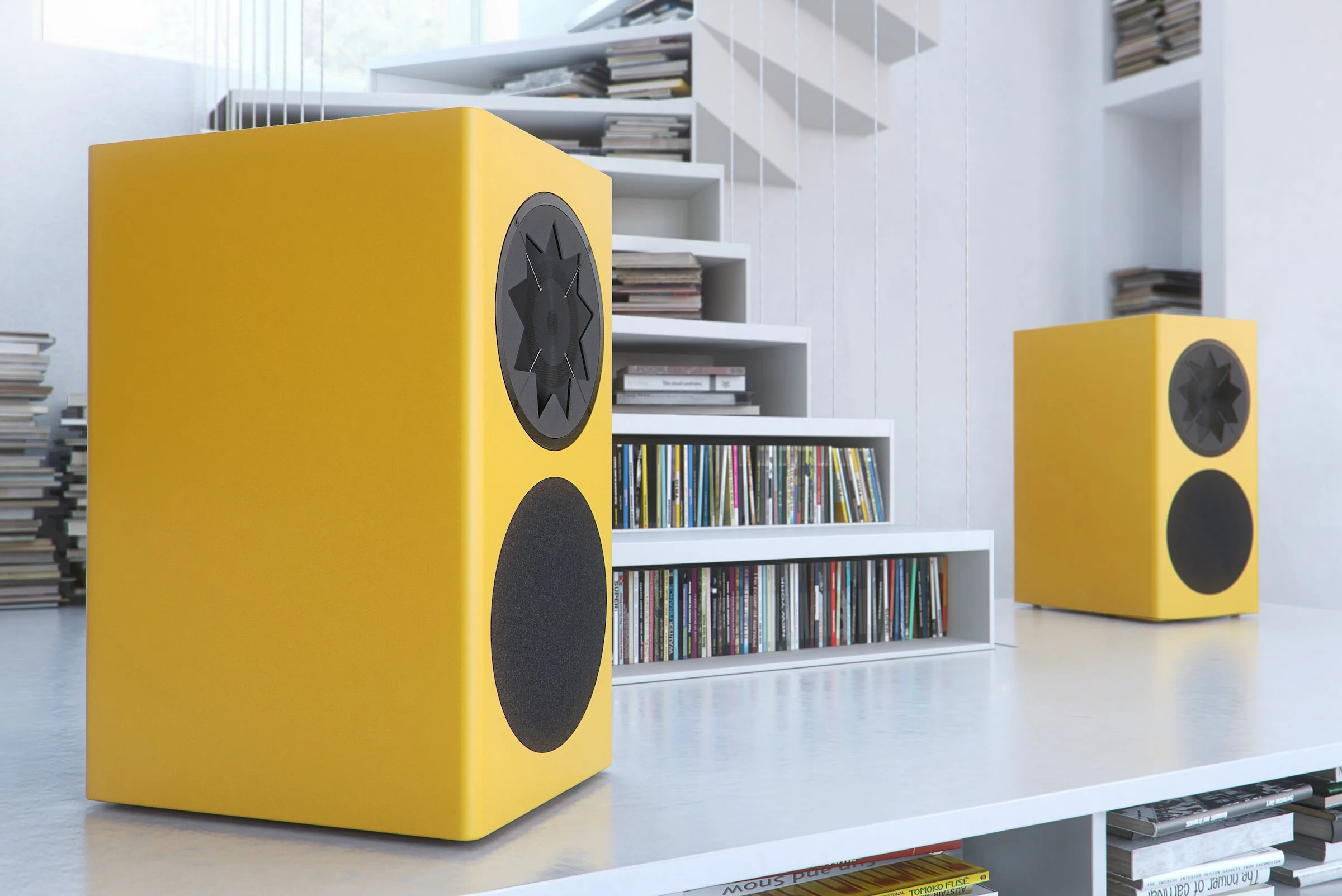 Manger Audio z1 Kompaktlautsprecher in gelb auf einem weißen Sideboard mit CDs im Hintergrund 