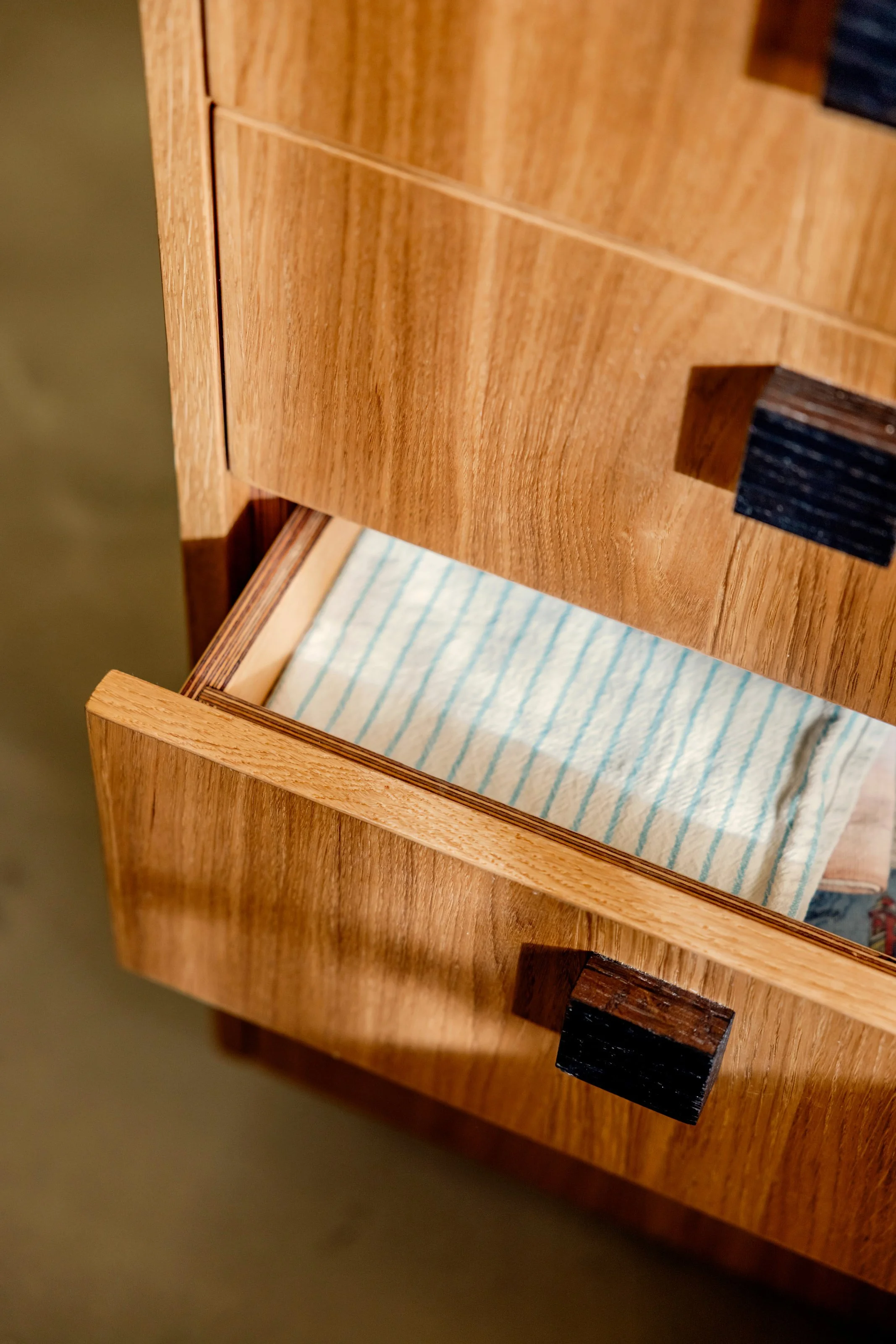 Close-up of a wooden drawer with a striped fabric lining inside.