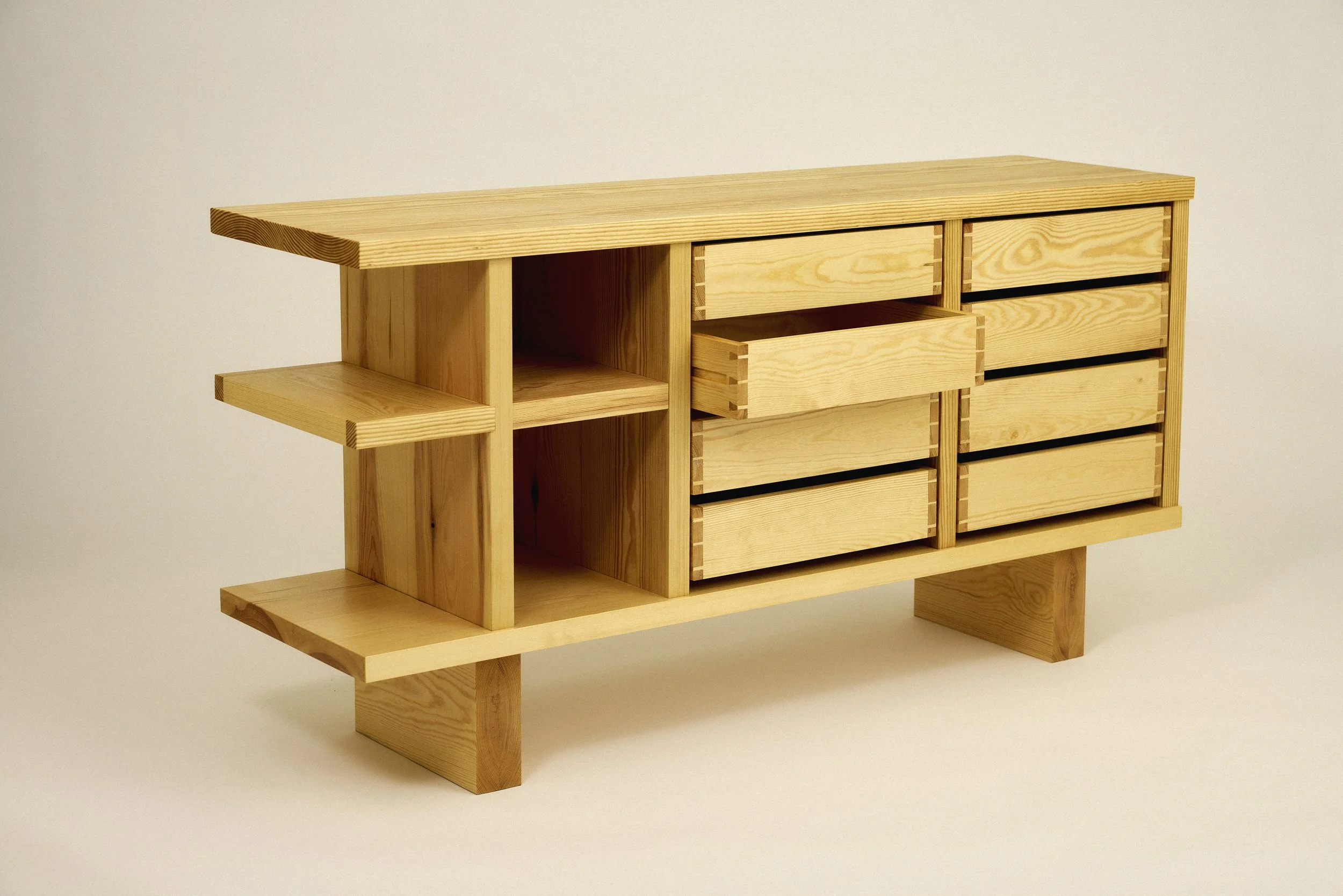 A wooden multi-level shelving unit with open shelves and drawers, made of solid pine. Japanese, Scandinavian, bauhaus style.