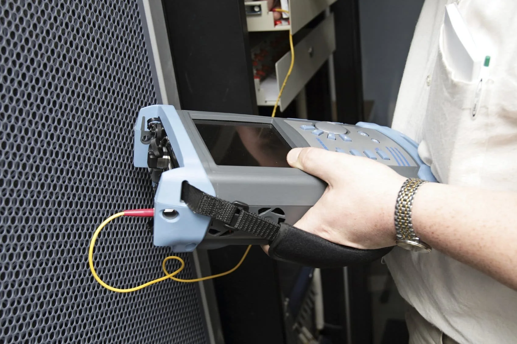 Une personne utilisant un appareil de test de réseau électronique avec des câbles connectés à une grille métallique.