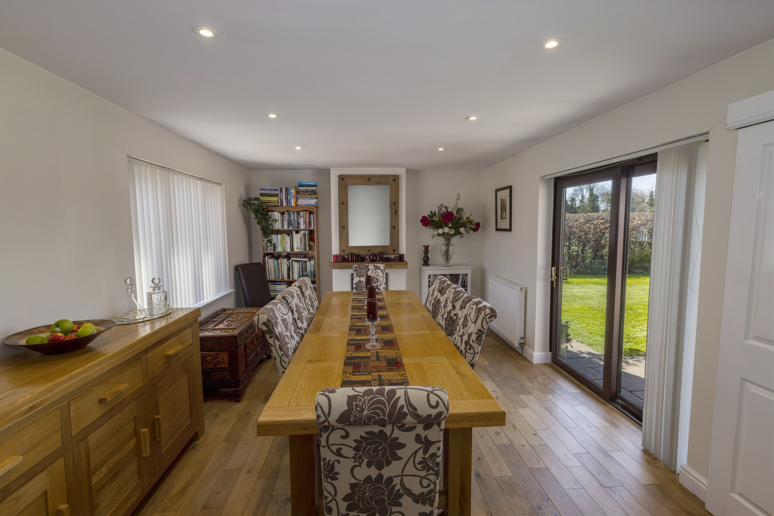 The inside of a house which looks very neat and tidy and professionally lit with a large dining table in the middle of the room.