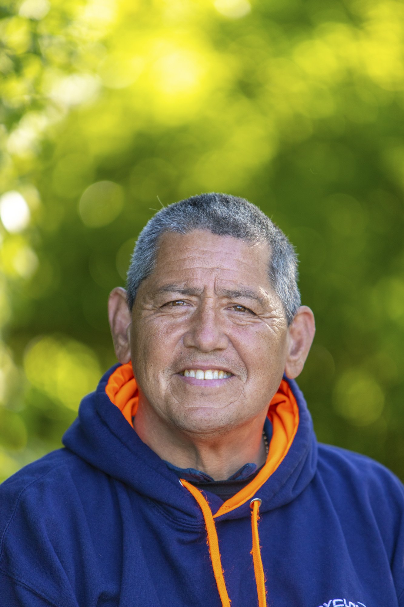 A man is photographed outdoors in lovely natural light with beautiful shallow depth of field bokeh balls in the background behind.