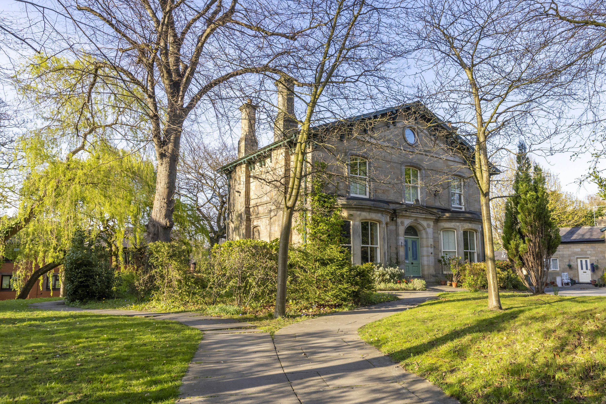 A building surrounded by bare trees outdoors on a sunny day.
