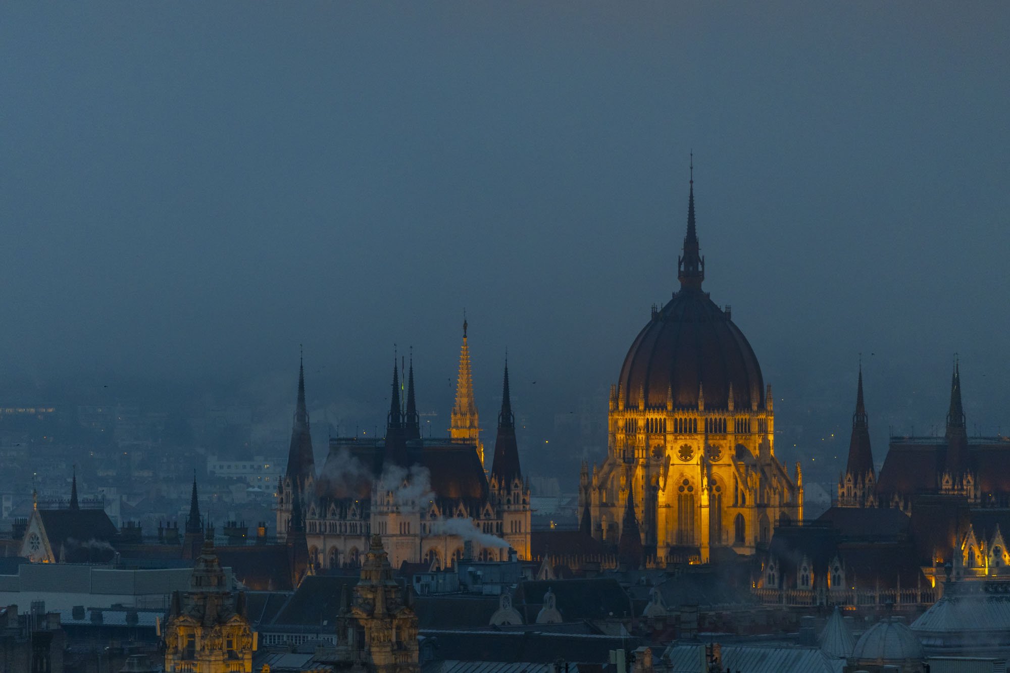The Hungarian Parliament building is lit up at night in the blue hour.