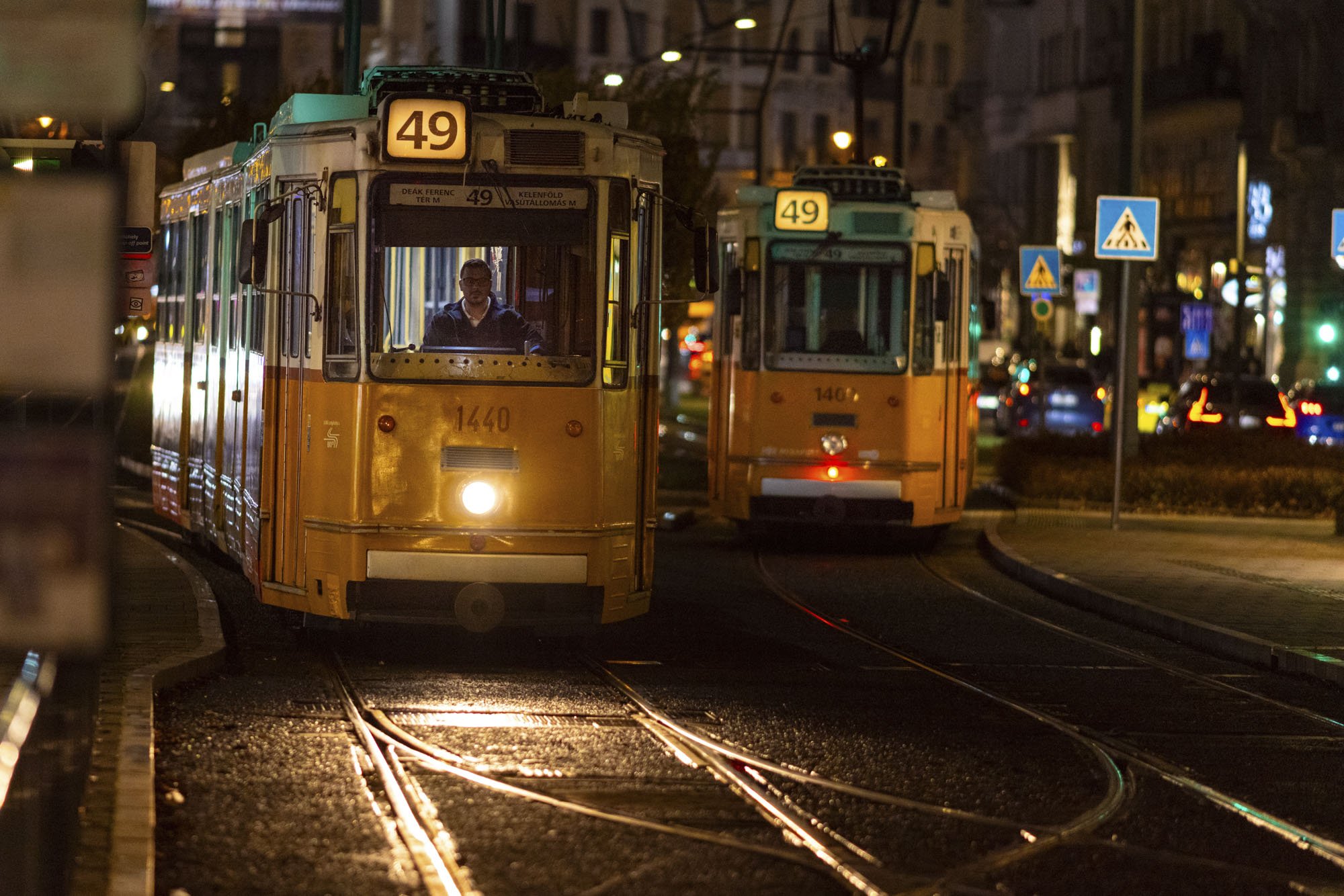 A tram rides on tracks towards the camera at night in Budapest, Hungary.