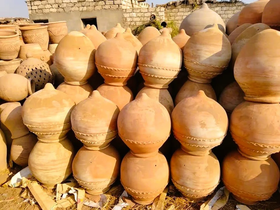 Egytptian Clay Terrecotta pottery jars stacked outdoors with a brick wall in the background
