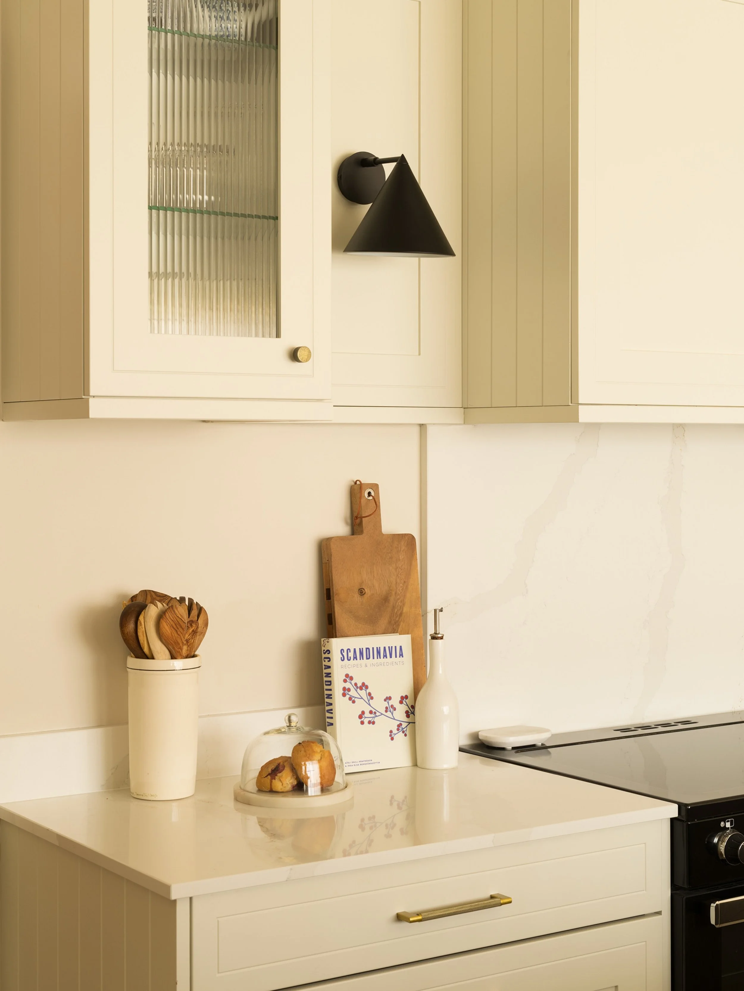 Traditional Nordic charm by Lou Joia Studio. Warm ivory cabinetry, delicate brass details, ribbed glass and a white marble stone create a kitchen that feels timeless and serene. Design by Lou Joia Studio, photographed by Johnny McMillan #kitchen #des