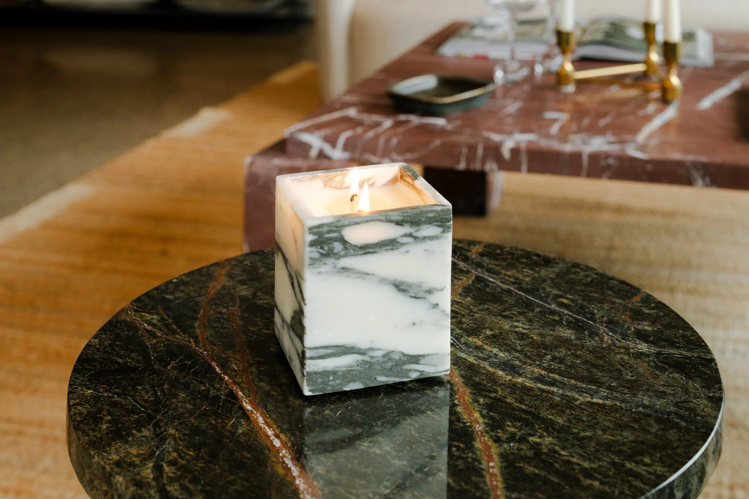 A lit white marble candle holder on a round black marble table.