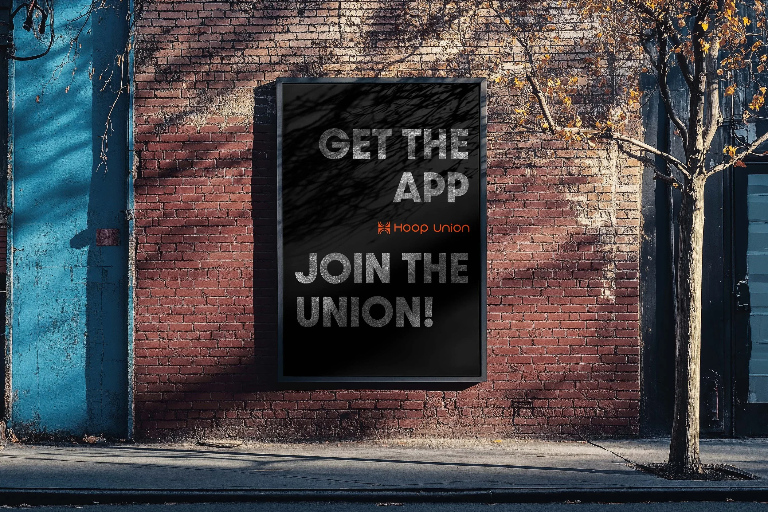A black poster on a brick wall with the text 'GET THE APP' and 'JOIN THE UNION!' and the Hoop Union logo below.