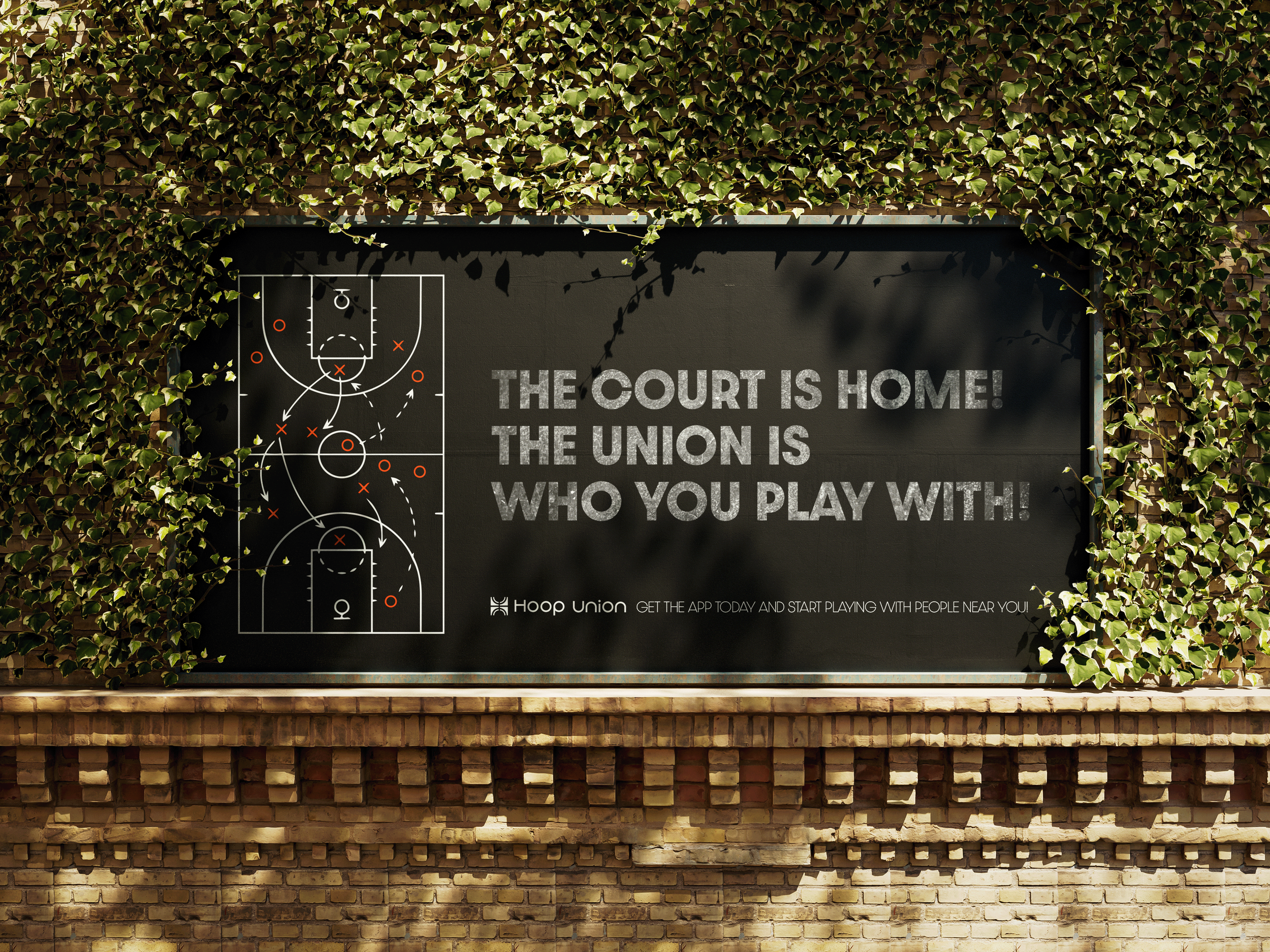 A large black sign with gray text reading, 'The court is home! The union is who you play with!' is mounted on a brick wall and surrounded by green ivy leaves.