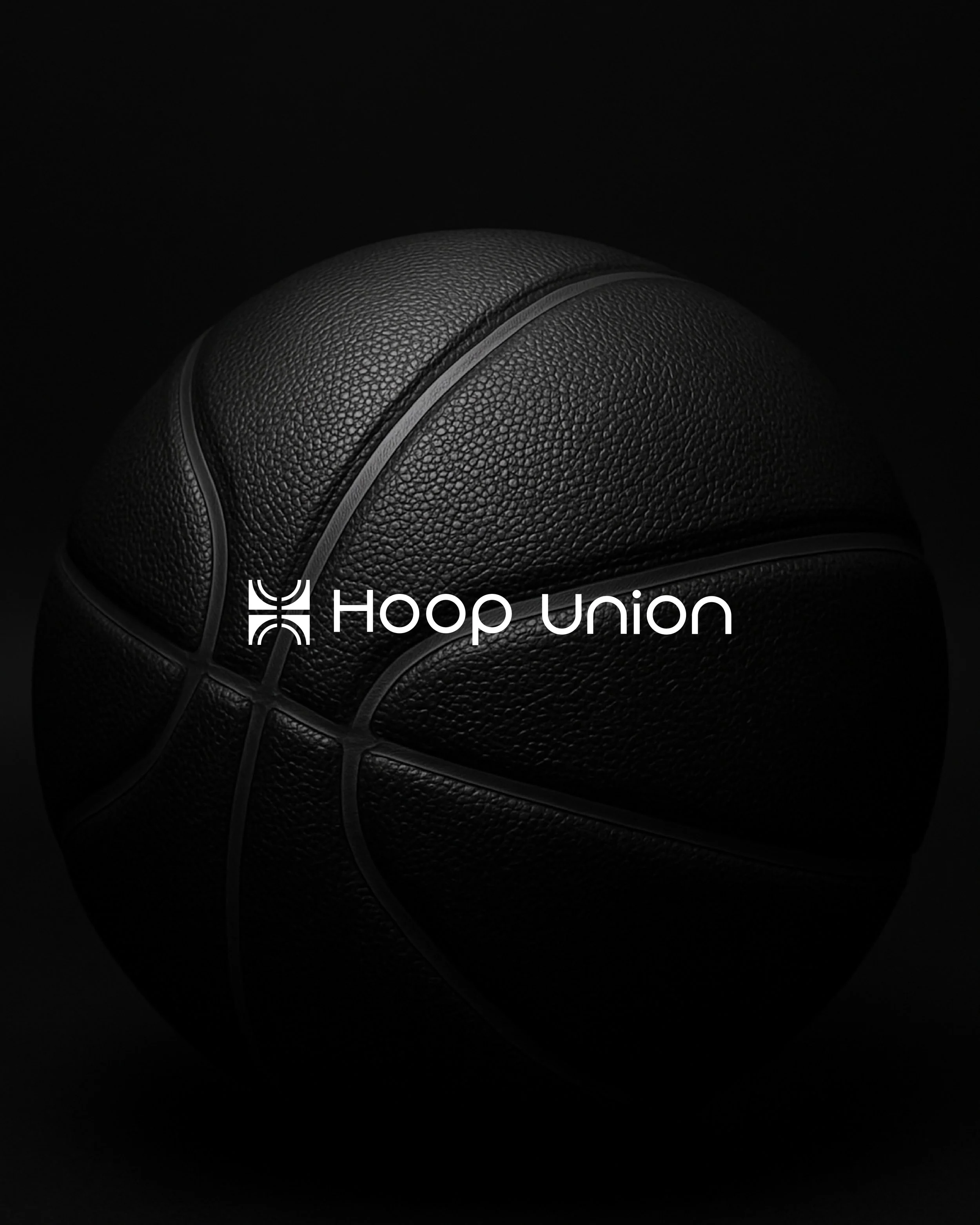 Close-up of a black leather basketball with the Hoop Union logo in white on a dark background.