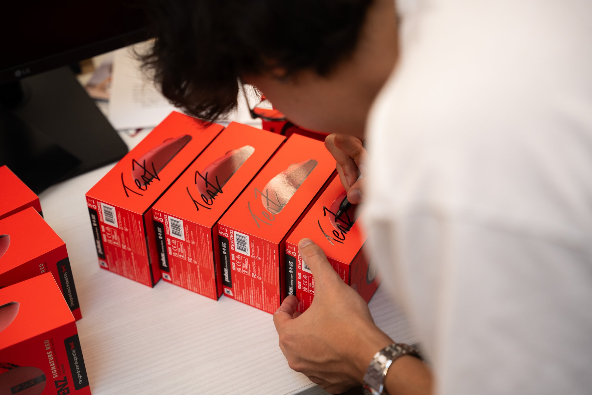 Person signing or labeling boxes of KN95 masks on a table.