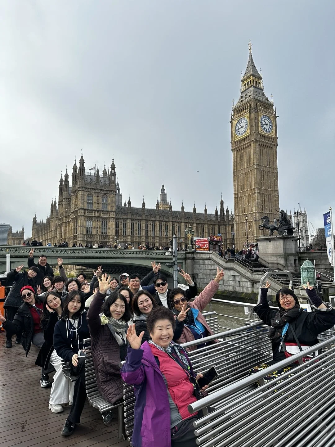 Group of tourists taking a photo in front of Big Ben and the Houses of Parliament in London, England.