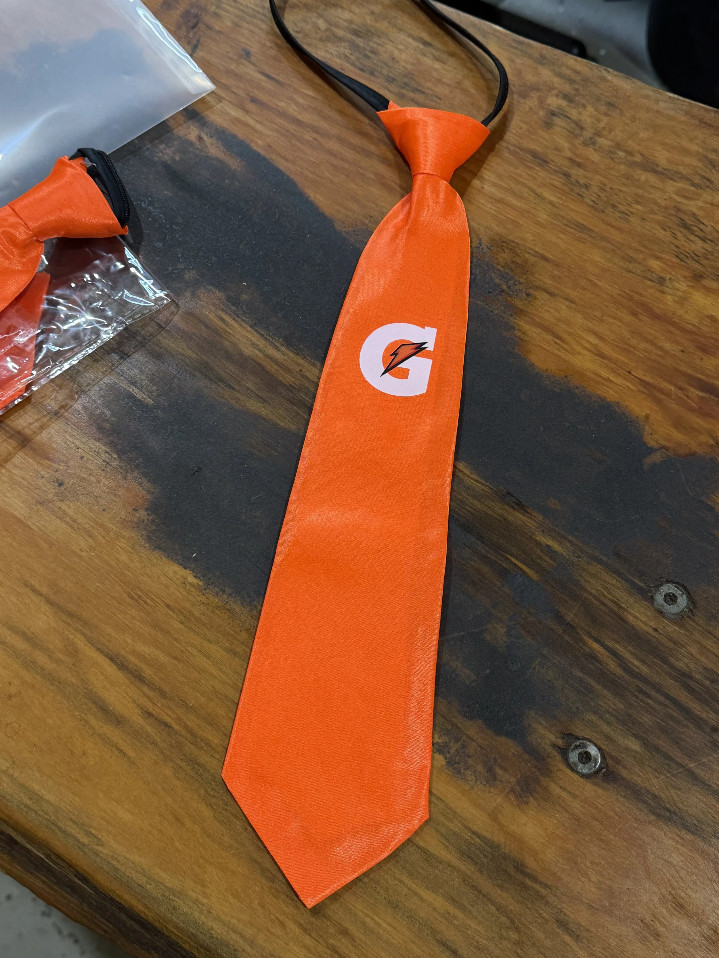 An orange Gatorade-branded necktie lying on a wooden surface.
