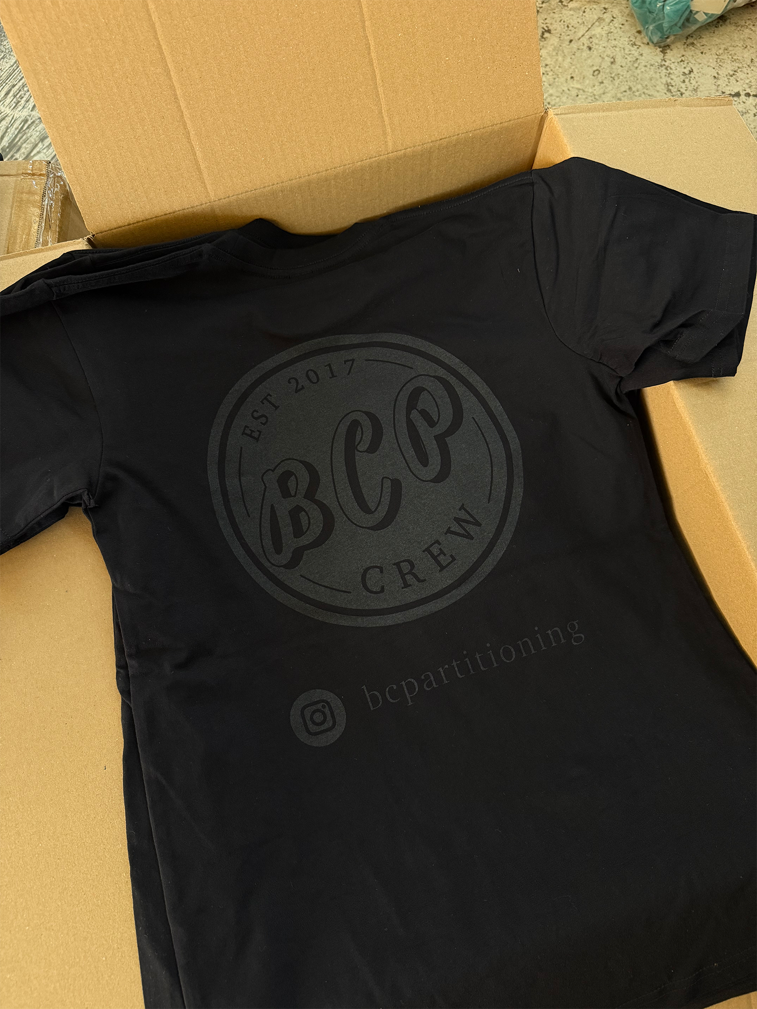 Black T-shirt with gray logo reading 'BCP Crew', 'Est 2017', and Instagram handle 'bcpartitioning', inside a box.