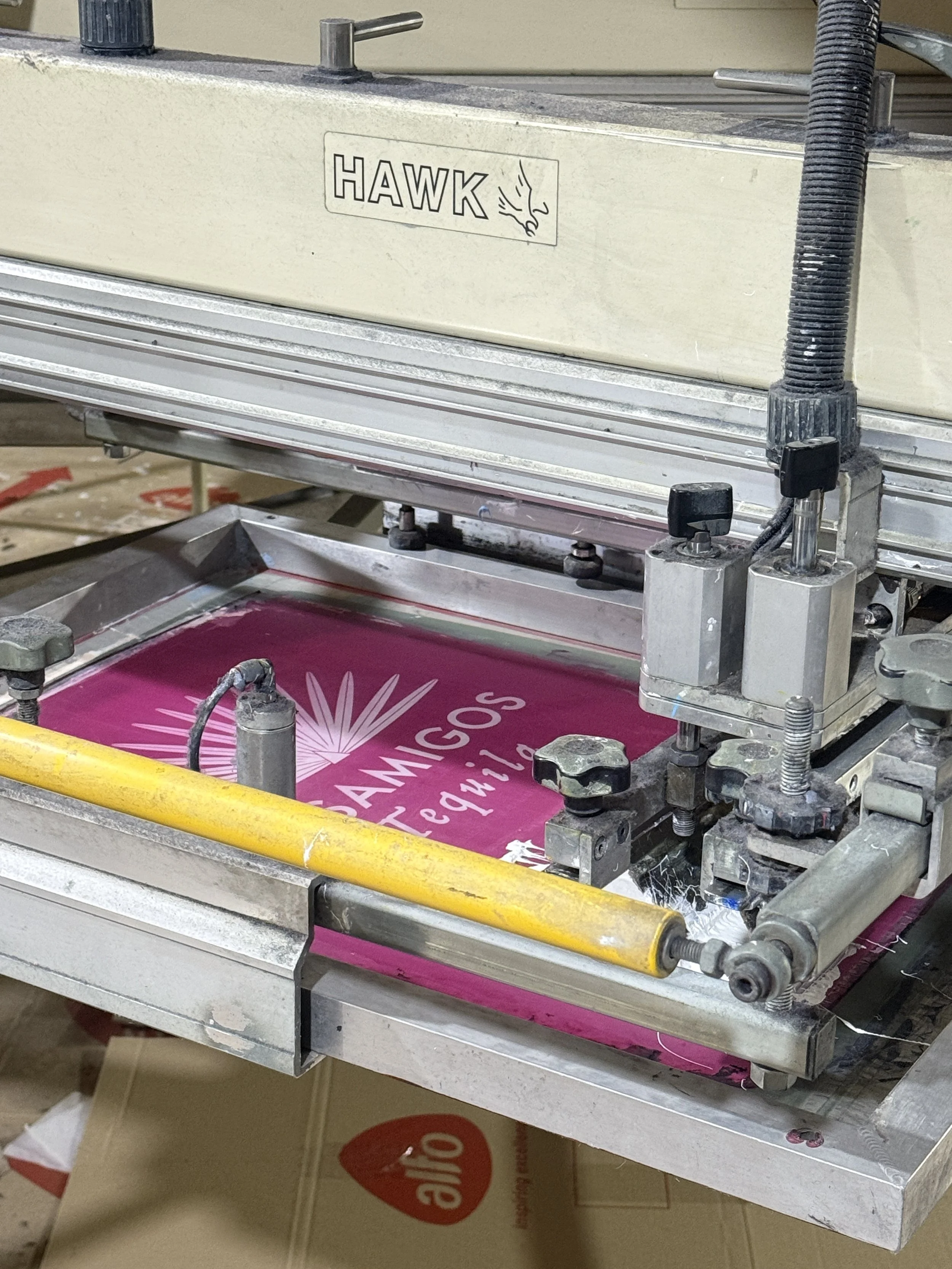A printing machine with the logo of Margaritas Tequileria being printed on a pink background.