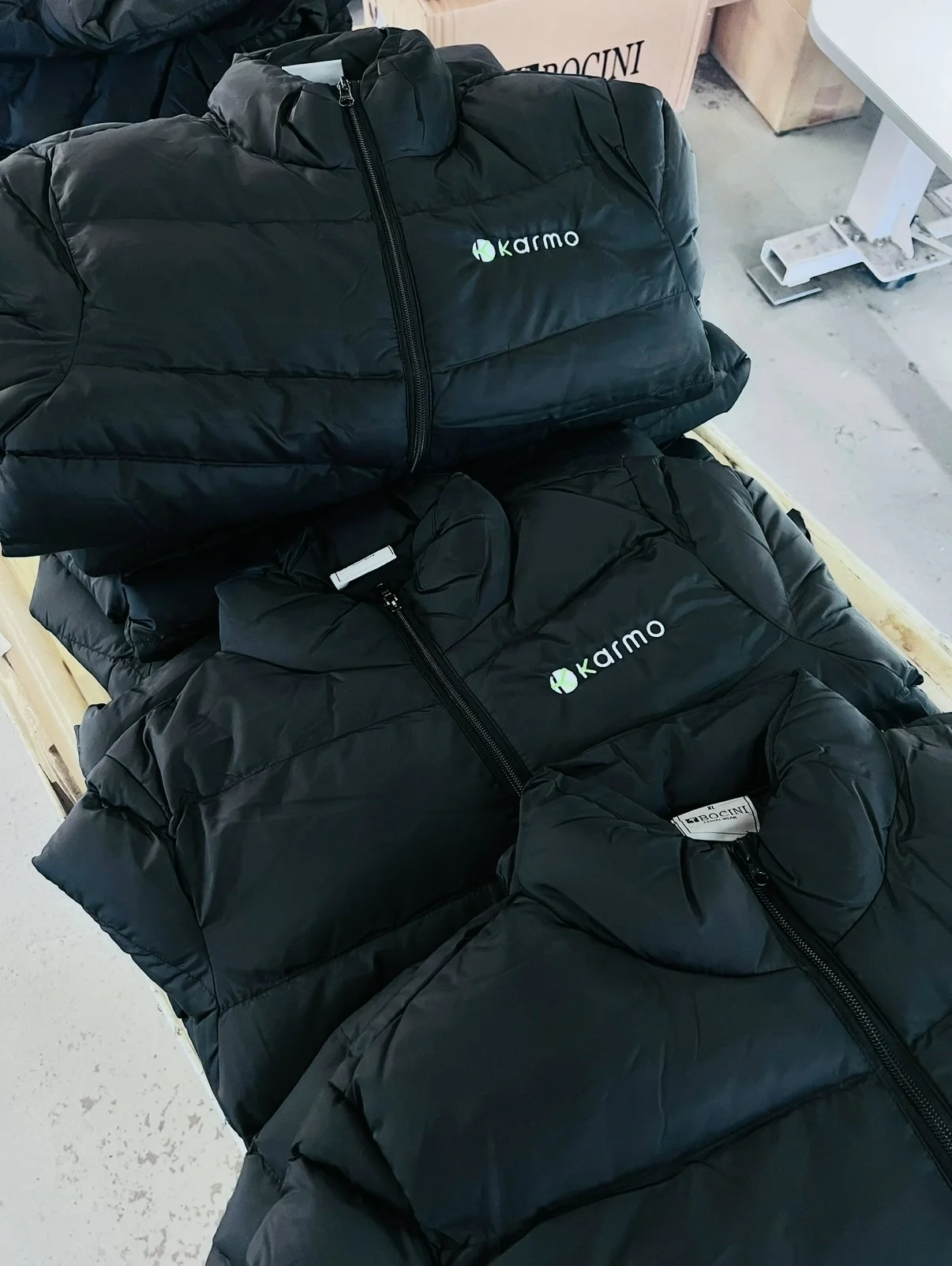 Three black puffer jackets with green and white logos lying on a table.
