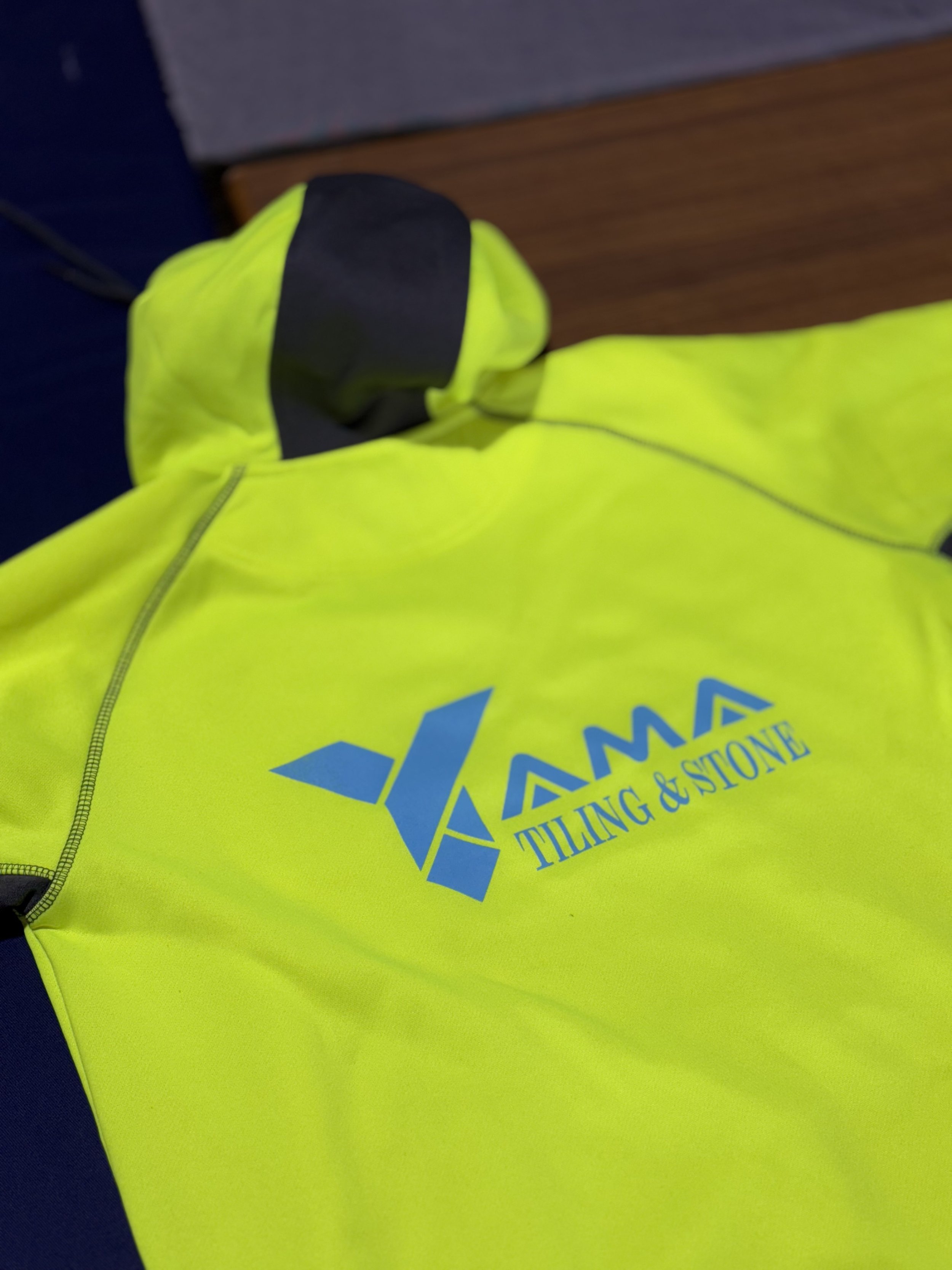 Bright yellow high-visibility jacket with a logo that reads 'YAMAM THING & STONE' on the chest area.