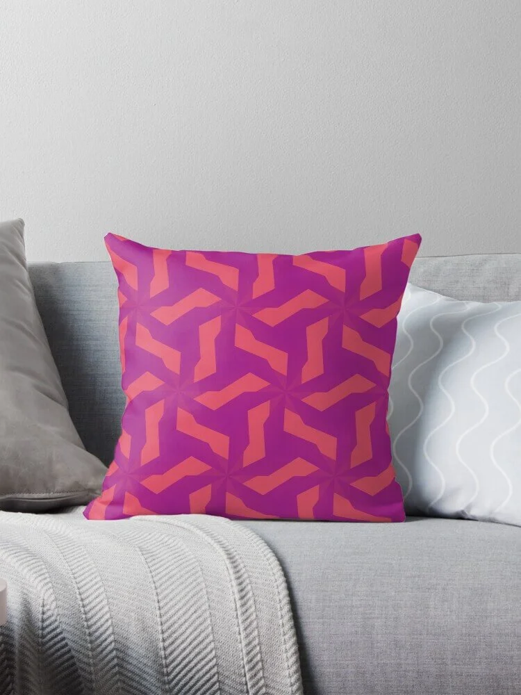 Decorative pillow with purple and pink geometric pattern on a light gray sofa in front of a plain white wall.