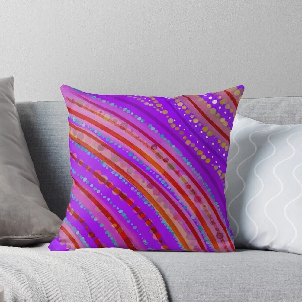 Purple decorative throw pillow with colorful diagonal dotted and stripe pattern on a light-colored sofa.