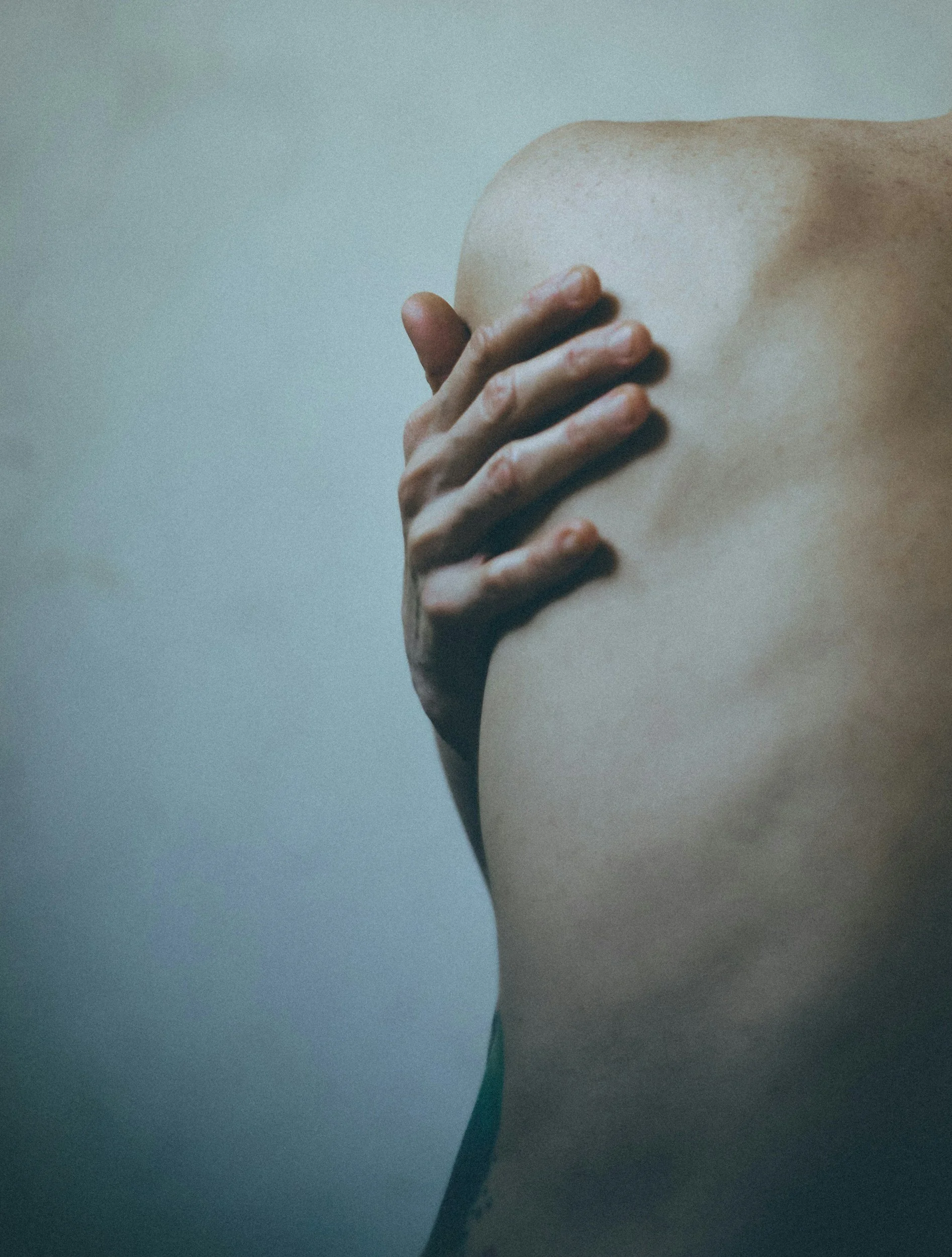 A person holding their own body in a gentle embrace, representing the self-nurturing and soothing experience of Rahanni Celestial Healing.
