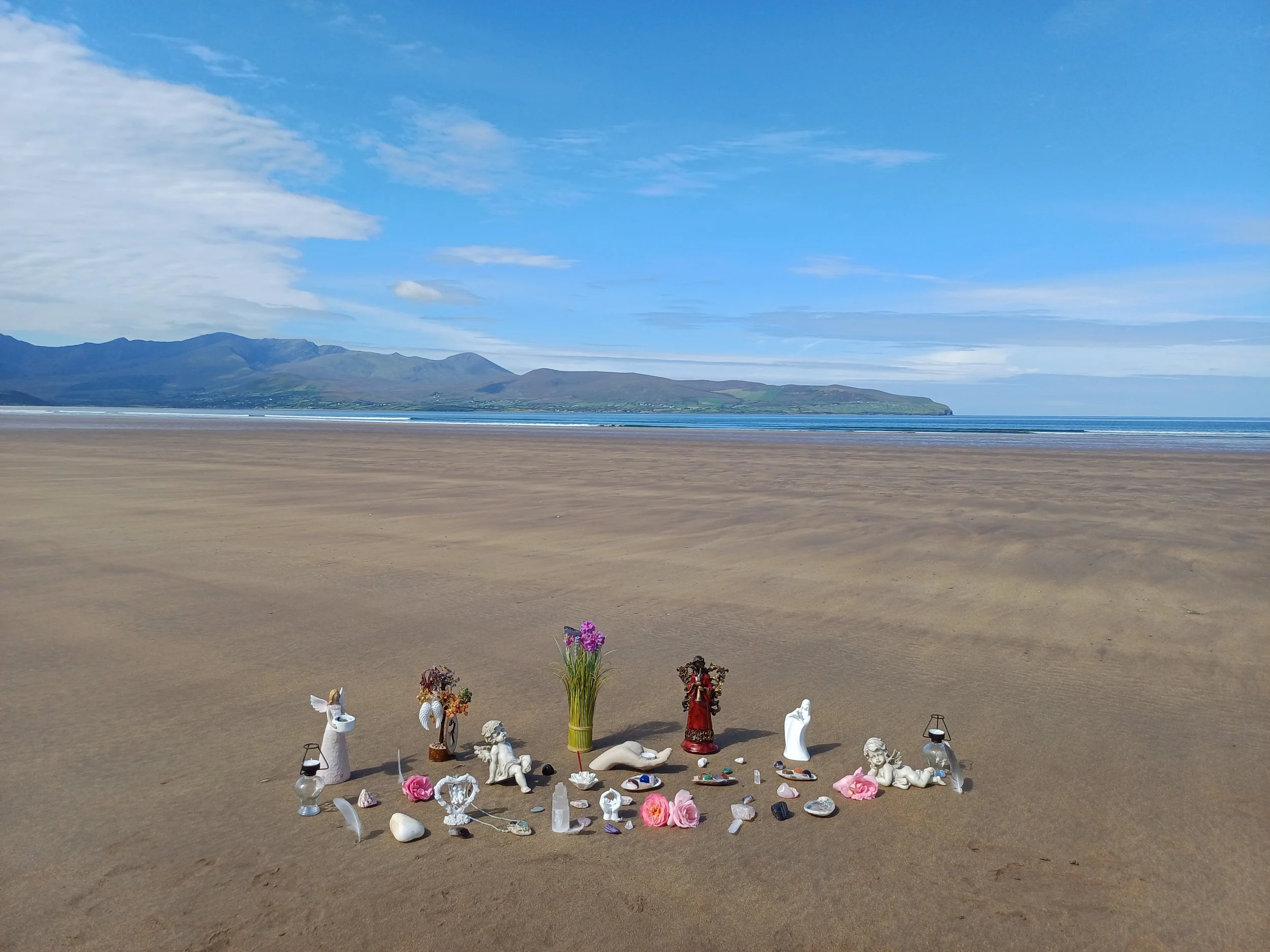 An altar set up for Rahanni Celestial Healing on a beach, featuring crystals and angelic figurines, provided by Tides of Spirit.