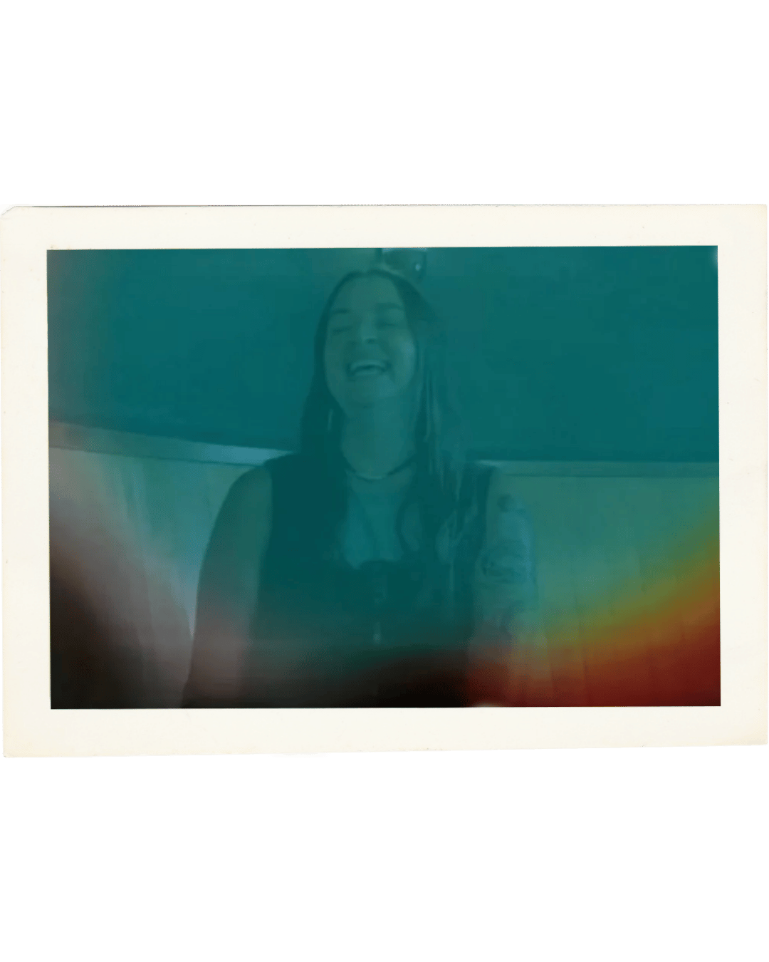A faded Polaroid-style photo of a woman with dreadlocks laughing, set against a neutral background.