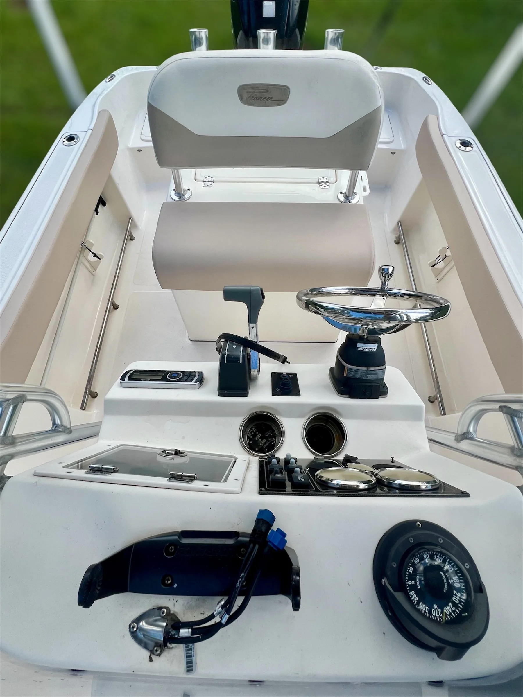 View of the steering console of a boat, including a steering wheel, throttle, gauges, and various controls.