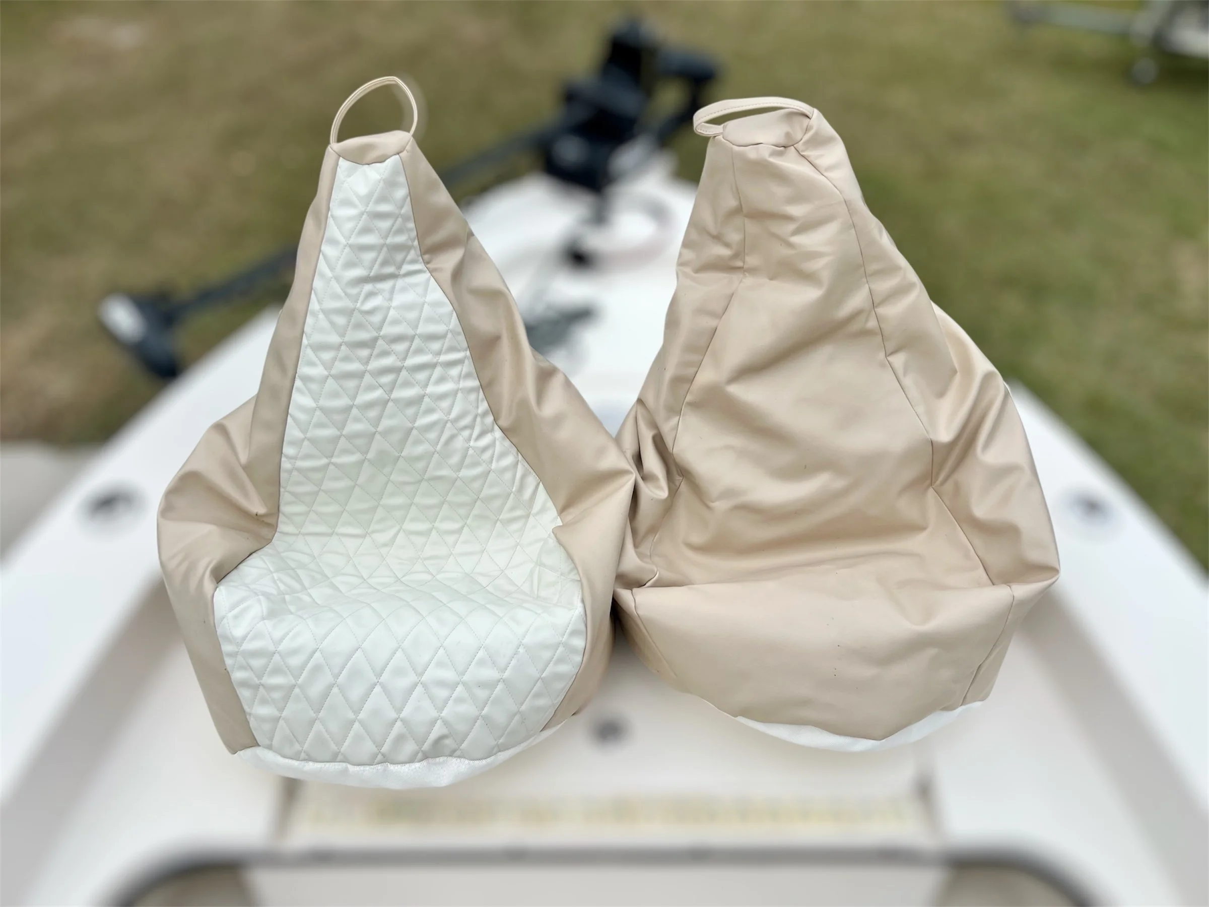 Two beige boat covers with white quilted interior lining, placed on a white surface outdoors.