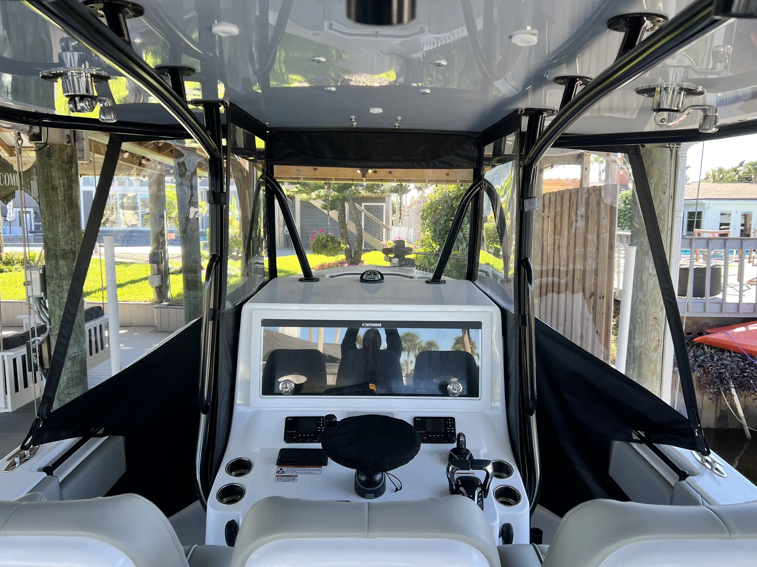 View of the boat's cockpit with steering wheel, control panels, and windshield, with outdoor scenery in the background.