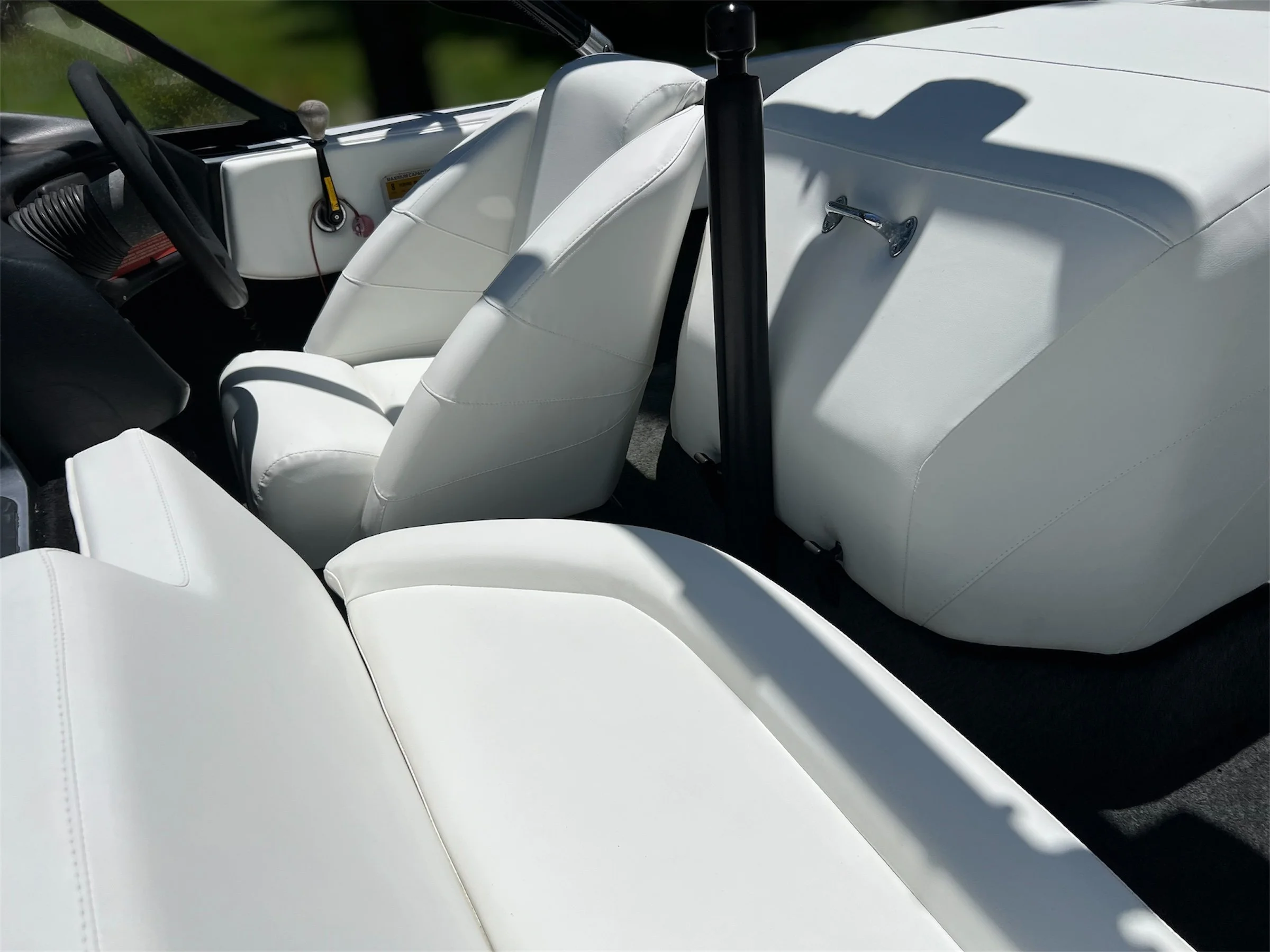 Interior of a white boat with white seats, steering wheel, and dashboard.