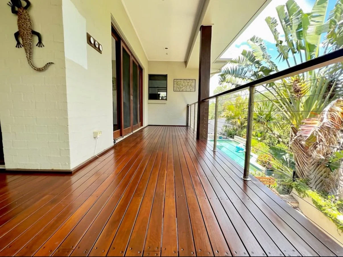 Undercover deck running along a rendered brick home, boards glossy after re-coating